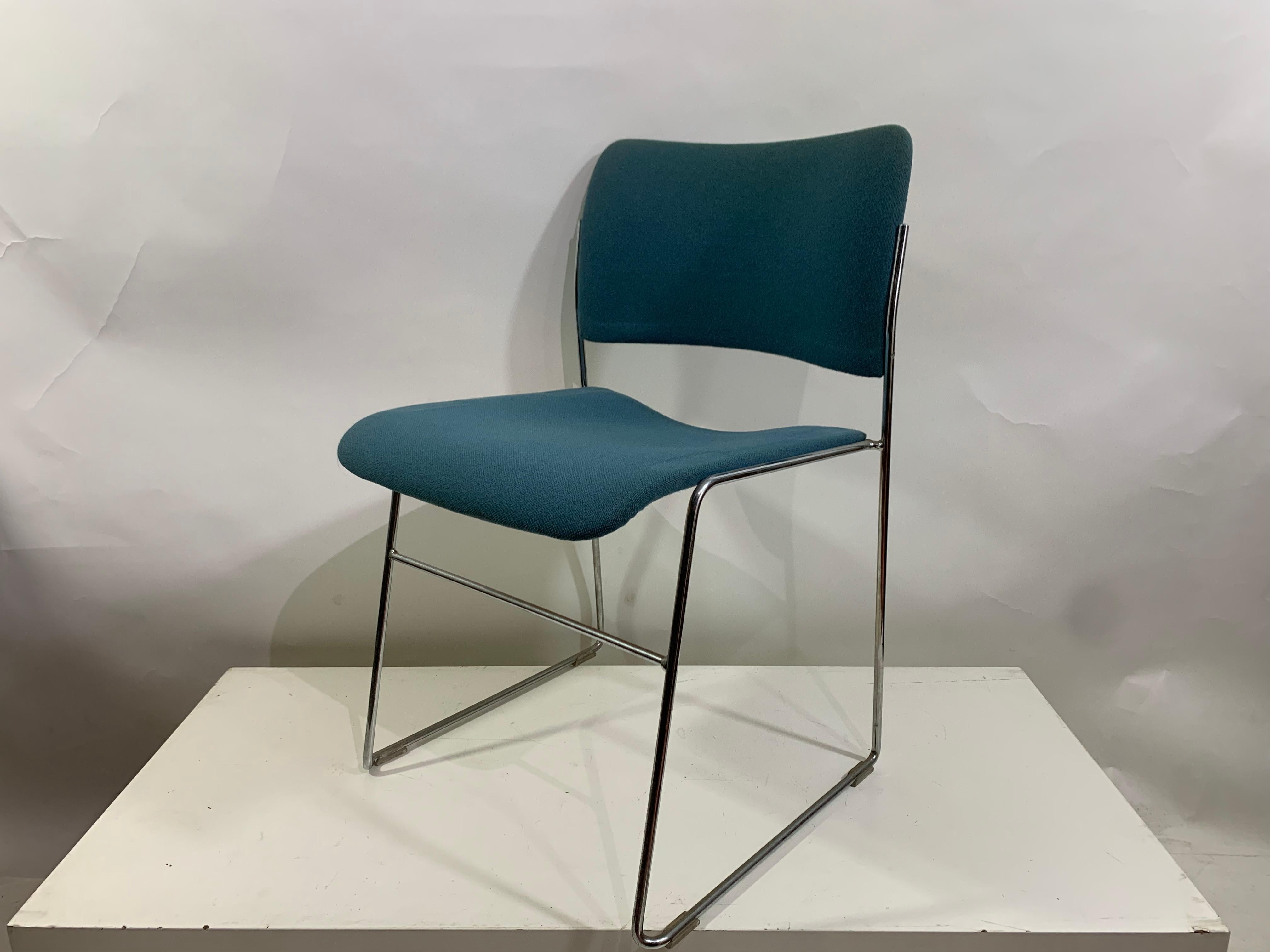 David Rowland's 4/40 dining chairs are very comfortable and have been awarded many design awards.
The chairs are stackable, made with metal wire chrome frame and metal sculpted seat and back in blue upholstery fabric.

This stackable chair can be