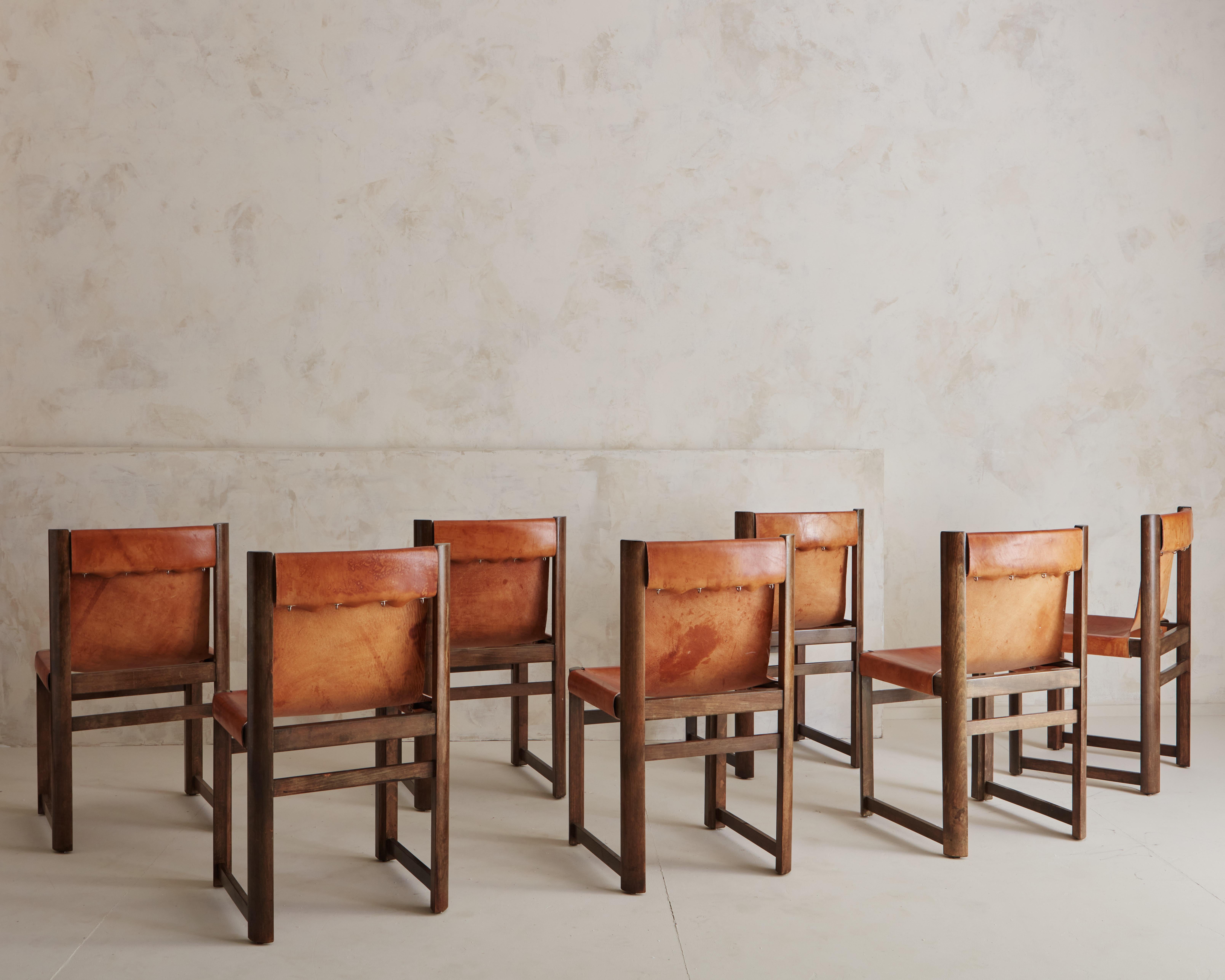 A Set of seven leather sling back chairs by Spanish interior designer and furniture maker, Jordi Vilanova. Silver locking mechanism that hold leather along the back and side of chairs add another beautiful design element. Sourced in Northern Spain.