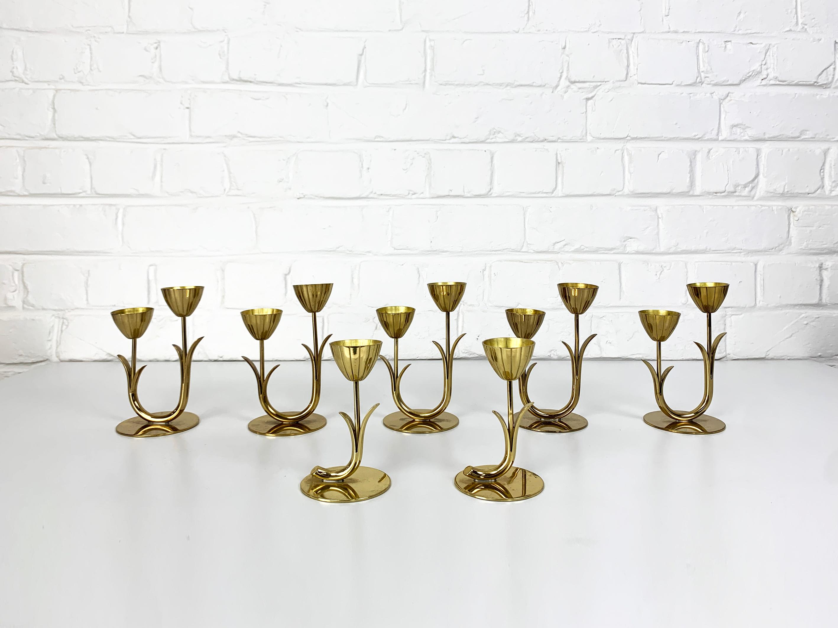 Set of 7 Swedish Modernist candelabra by Gunnar Ander. Produced by Ystad-Metall, located in the town of Ystad in Sweden. 

Candle-holders in solid brass. Organic design of stylised flowers and leaves attached to a curved stem and placed on a