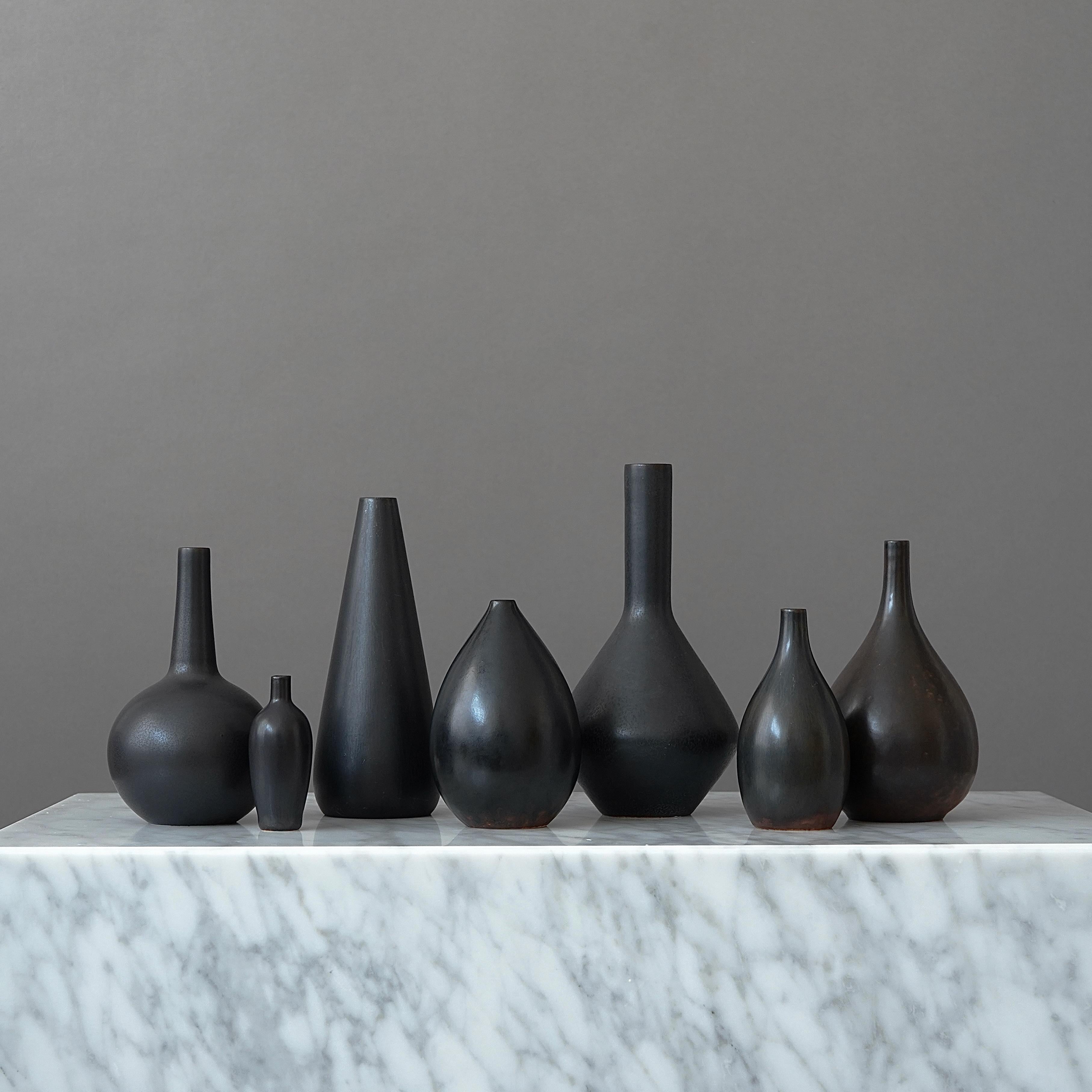 Ensemble de 7 beaux vases en grès avec une glaçure noire-brune étonnante.
Conçu par Carl-Harry Stålhane à Rörstrand, Suède, années 1950.

Excellent état. Signé 