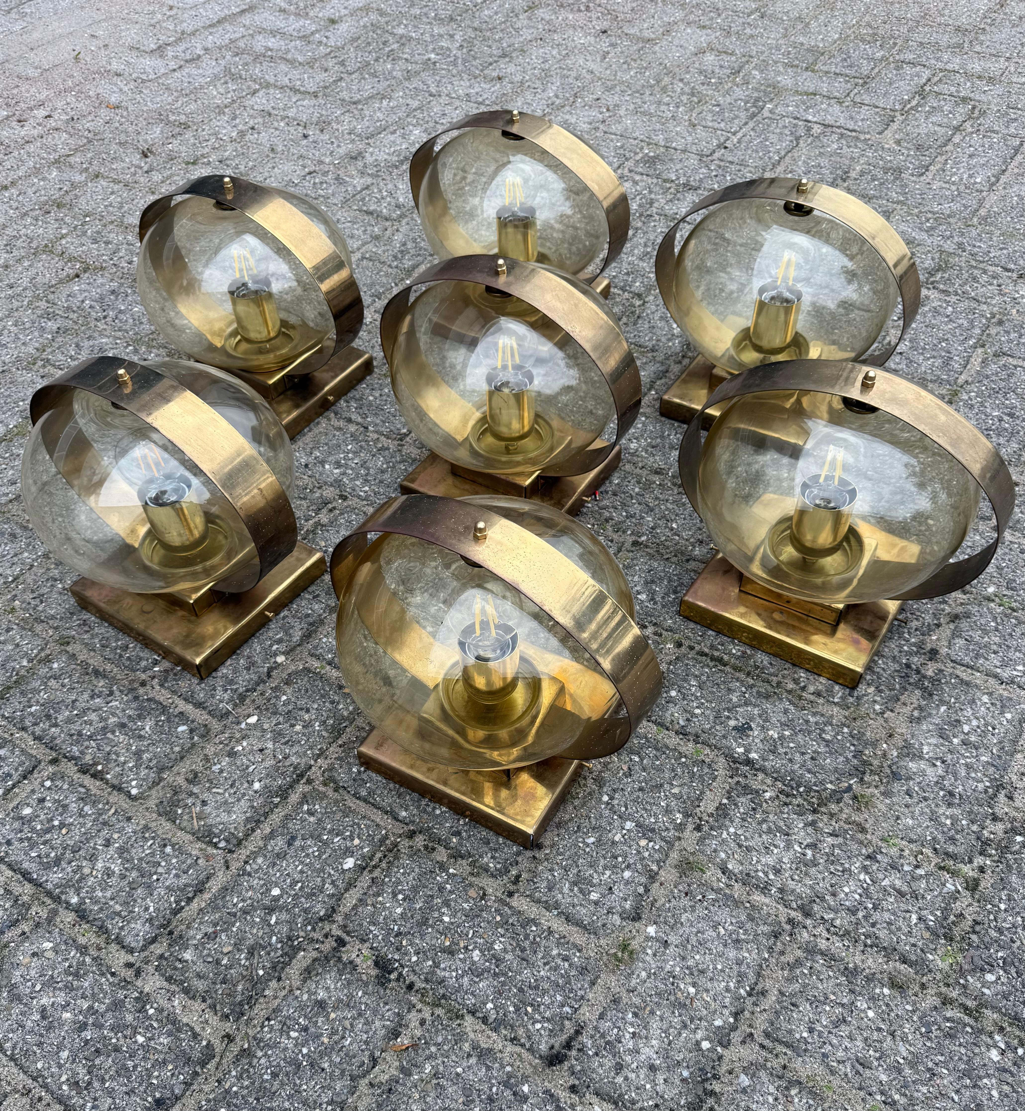 Timeless design and easy to mount wall sconces from the Midcentury era.

Timeless in design and effortlessly elegant, this beautiful set of seven vintage brass and smoked glass lights will bring warmth and atmosphere to any interior. Designed during