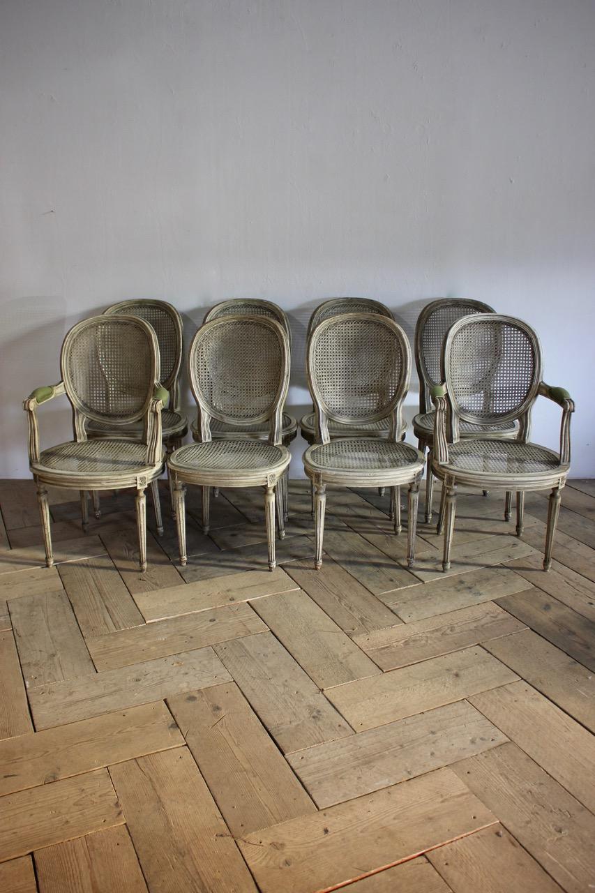 An elegant set of eight, circa 1930s French painted dining chairs in the Louis XVI taste, comprising two carvers and six chairs. Original cane and paint. 
Newly made cushions in green linen. This elegant set of painted chairs will work well in most