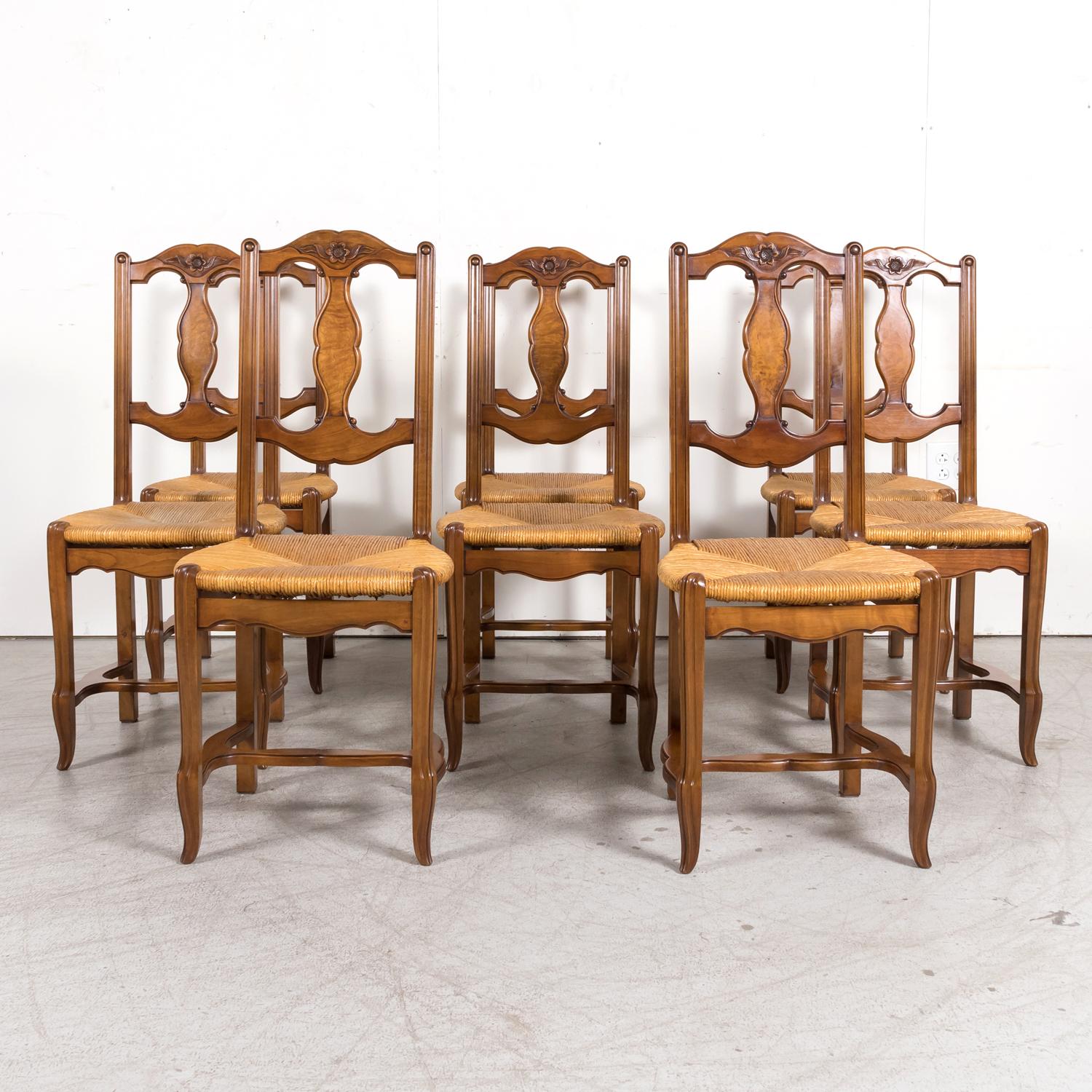 A set of eight 19th century antique Country French Louis XV style carved dining side chairs from Normandy, circa 1890s. Handcrafted in walnut, each of these antique dining chairs features a carved top rail having floral motifs with vertical slats.