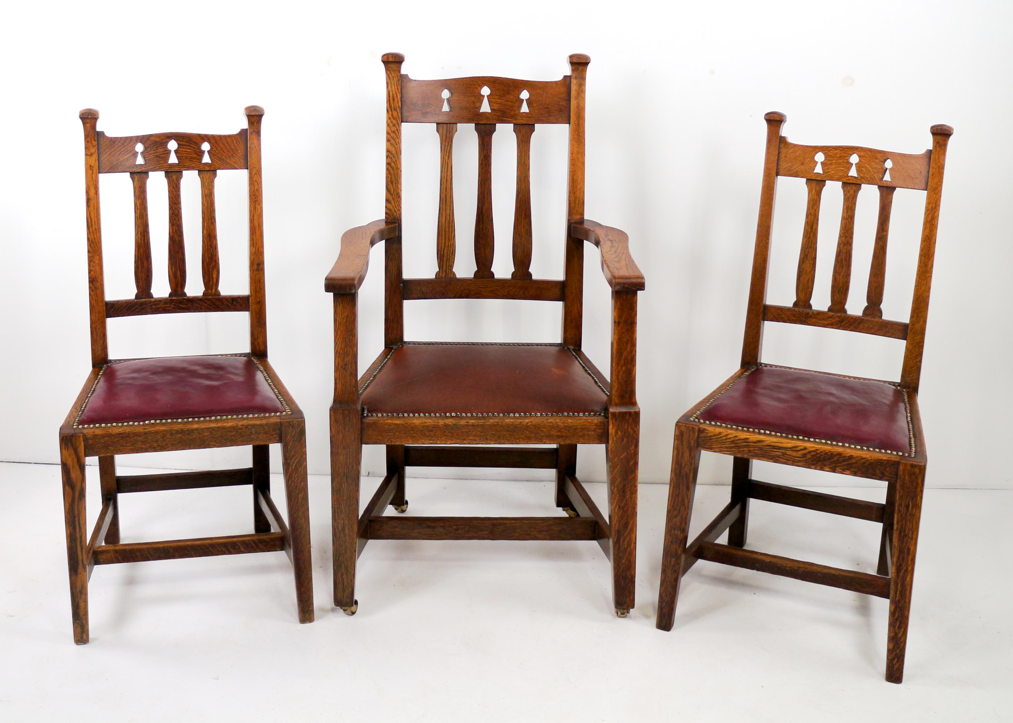 Un set di otto sedie da pranzo in rovere Arts & Crafts risalenti al 1890 circa.  Composto da due poltrone e sei sedie laterali, con decorazioni a forma di albero traforato sui poggiatesta e stecche dello schienale a forma di vaso, su gambe quadrate