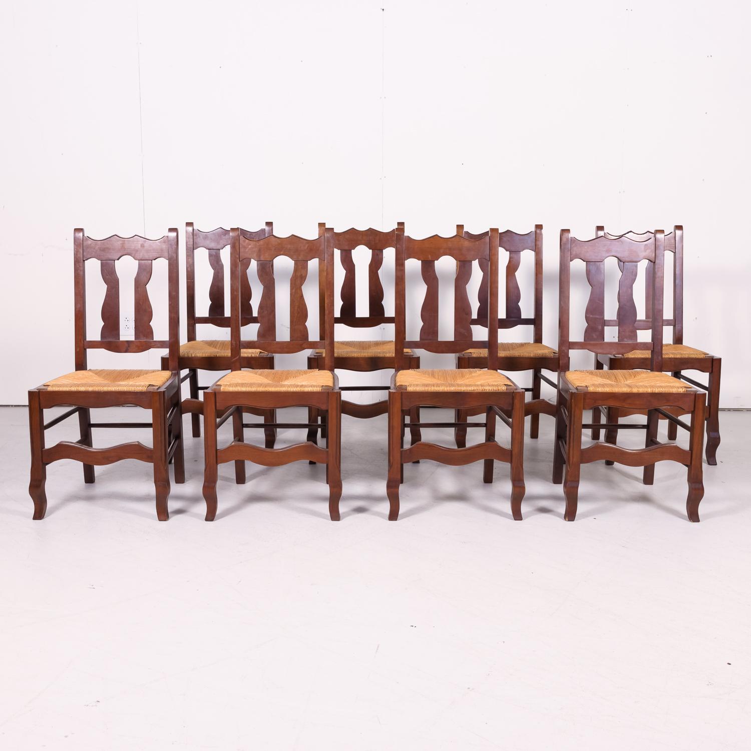 Set of 8 antique Country French hand carved oak dining chairs handcrafted in Normandy having carved backs with vertical slats and rush slip seats, circa 1920s. Raised on stylized cabriole legs joined by a carved front stretcher and turned side