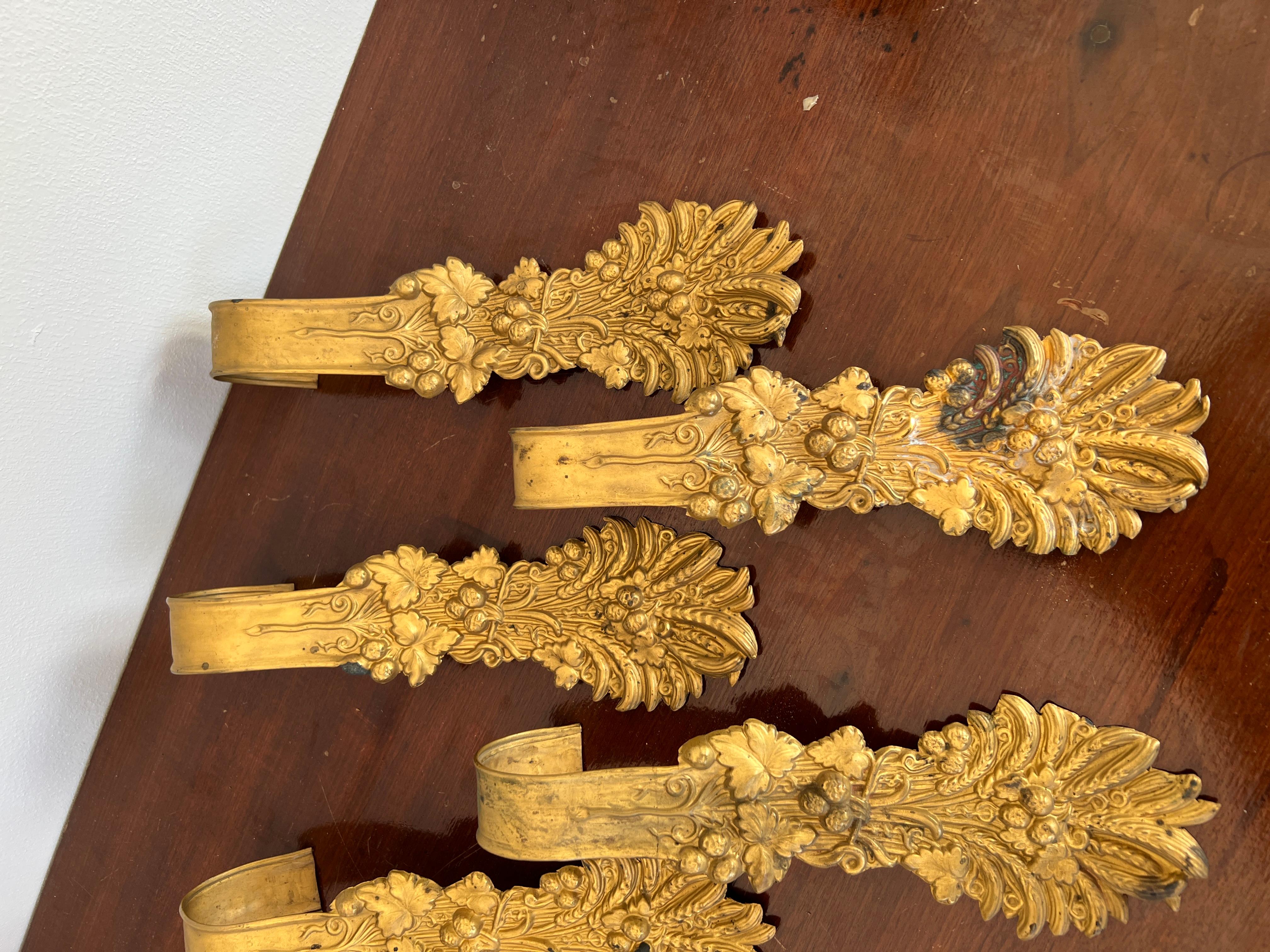 French, c. 1900.

A set of 8 antique pressed brass curtain tiebacks. They each feature acanthus leaf, foliate and grape motif with a scooped handle back. Apparently unmarked. Note: One is missing tip pin to verso as photographed.