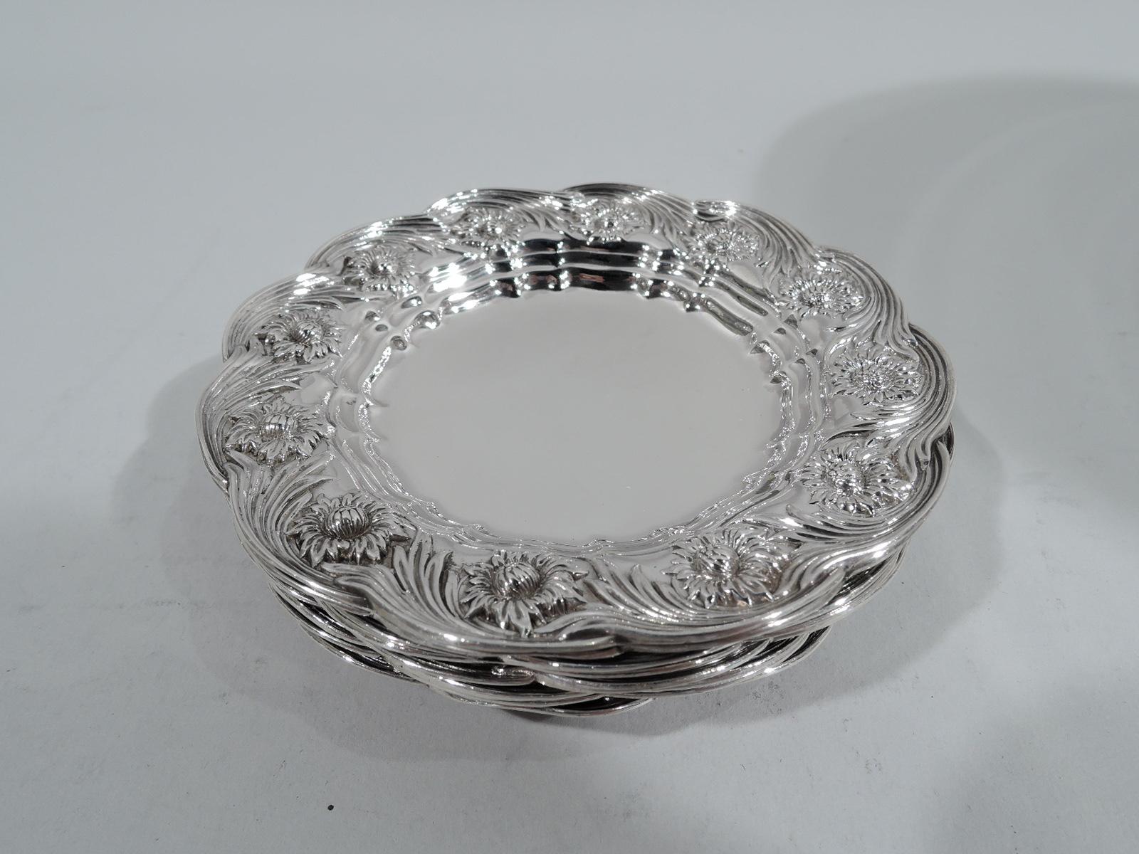 Set of 8 Chrysanthemum sterling silver butter pats. Made by Tiffany & Co. in New York. Plain and round well of which 6 gilt-washed and 2 plain. Shoulder has flower heads surrounded by rolling rinceaux-style tendrils. Rim scalloped. Fully marked