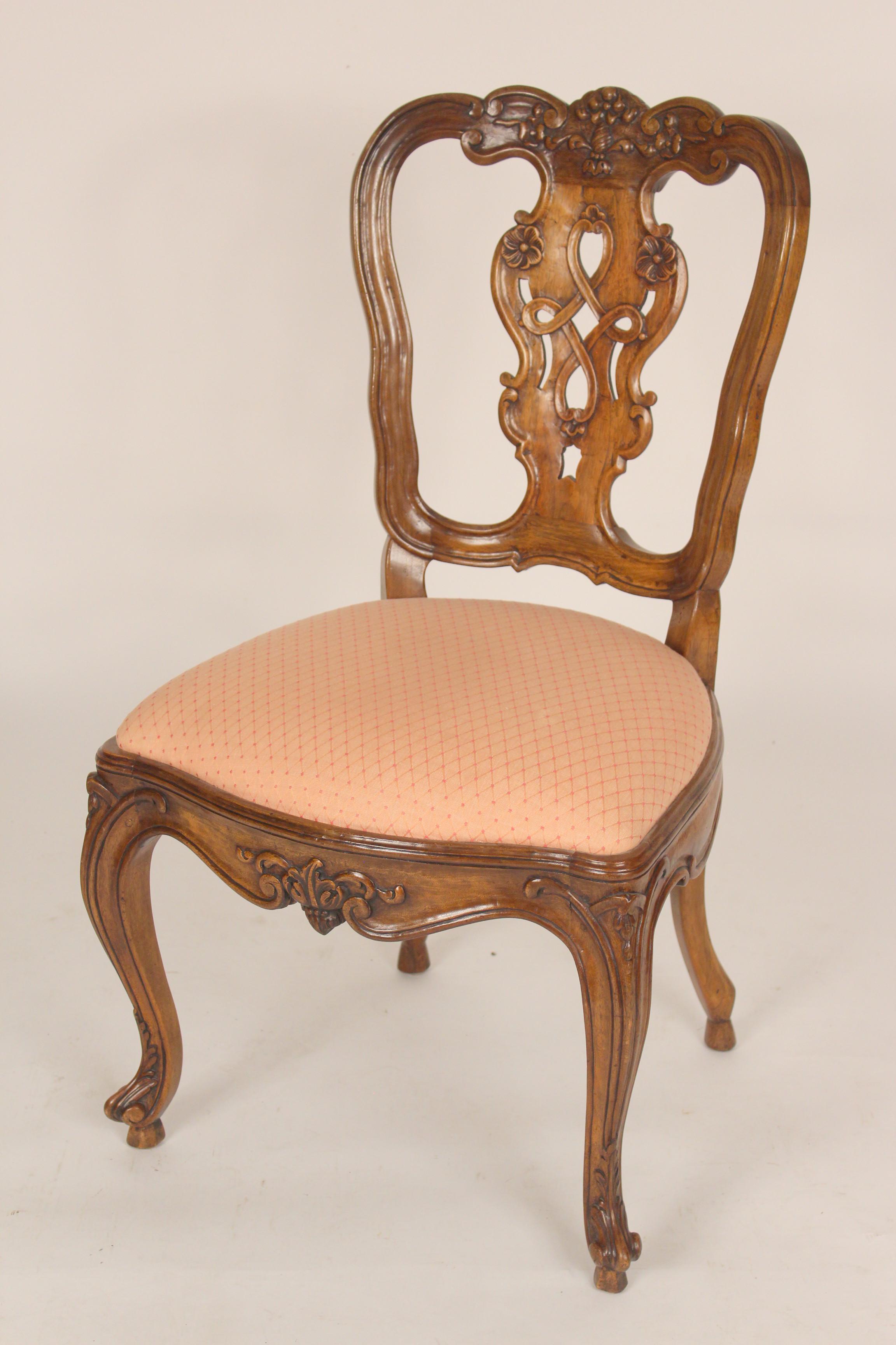 Set of 8 antique Louis XV provincial style walnut and beech wood dining room chairs, 19th century. With floral carved crest rails, back splats, apron and cabriole legs. Chairs have an excellent old patina. Mortise, tenon and peg construction.
