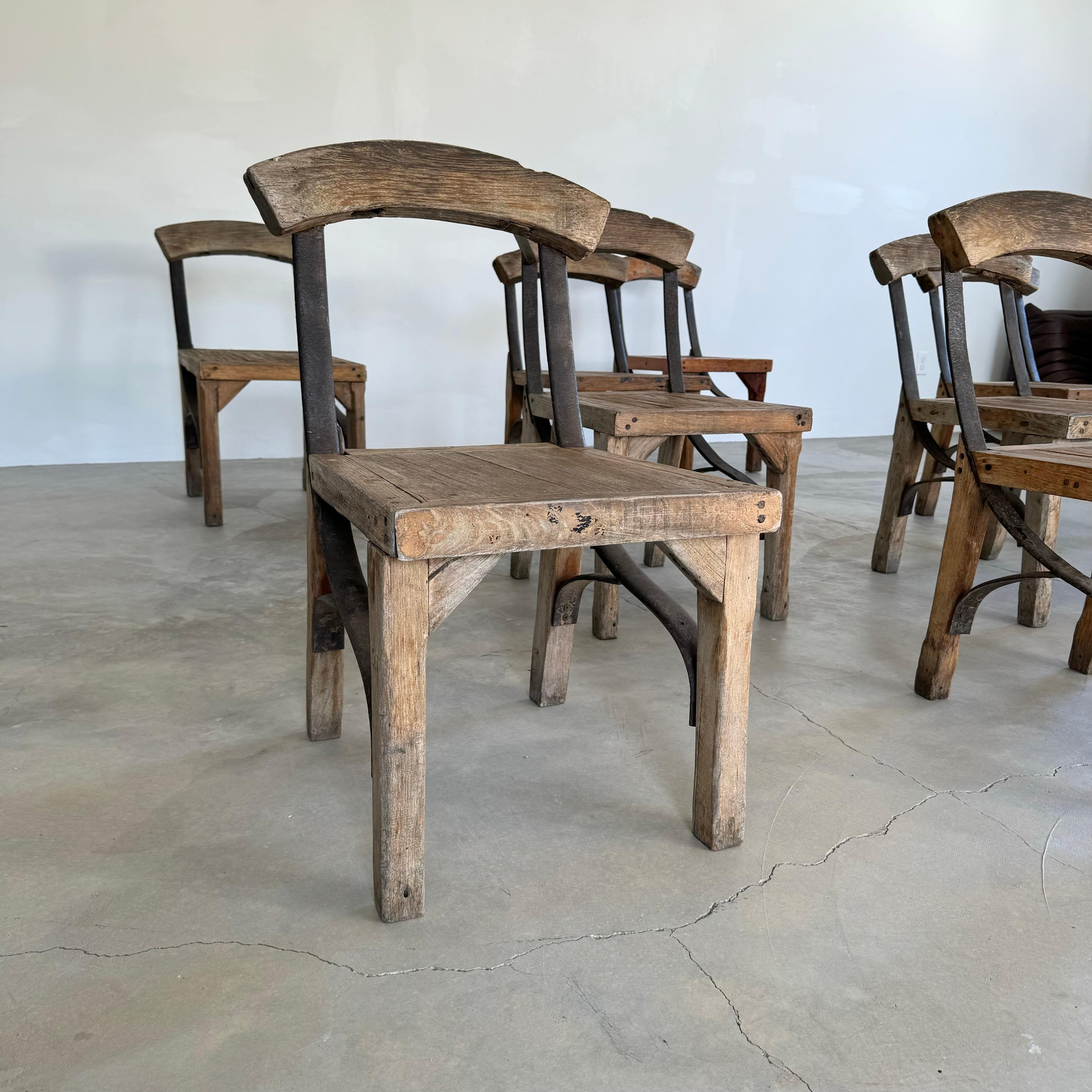 Incredible set of 8 antique oak and iron chairs. Handmade. Heavy and sturdy. Excellent age and patina to the wood and iron framing. Subtle curvature of the backboard is complimented by the rounded silhouettes of the metal frames. Robust yet elegant
