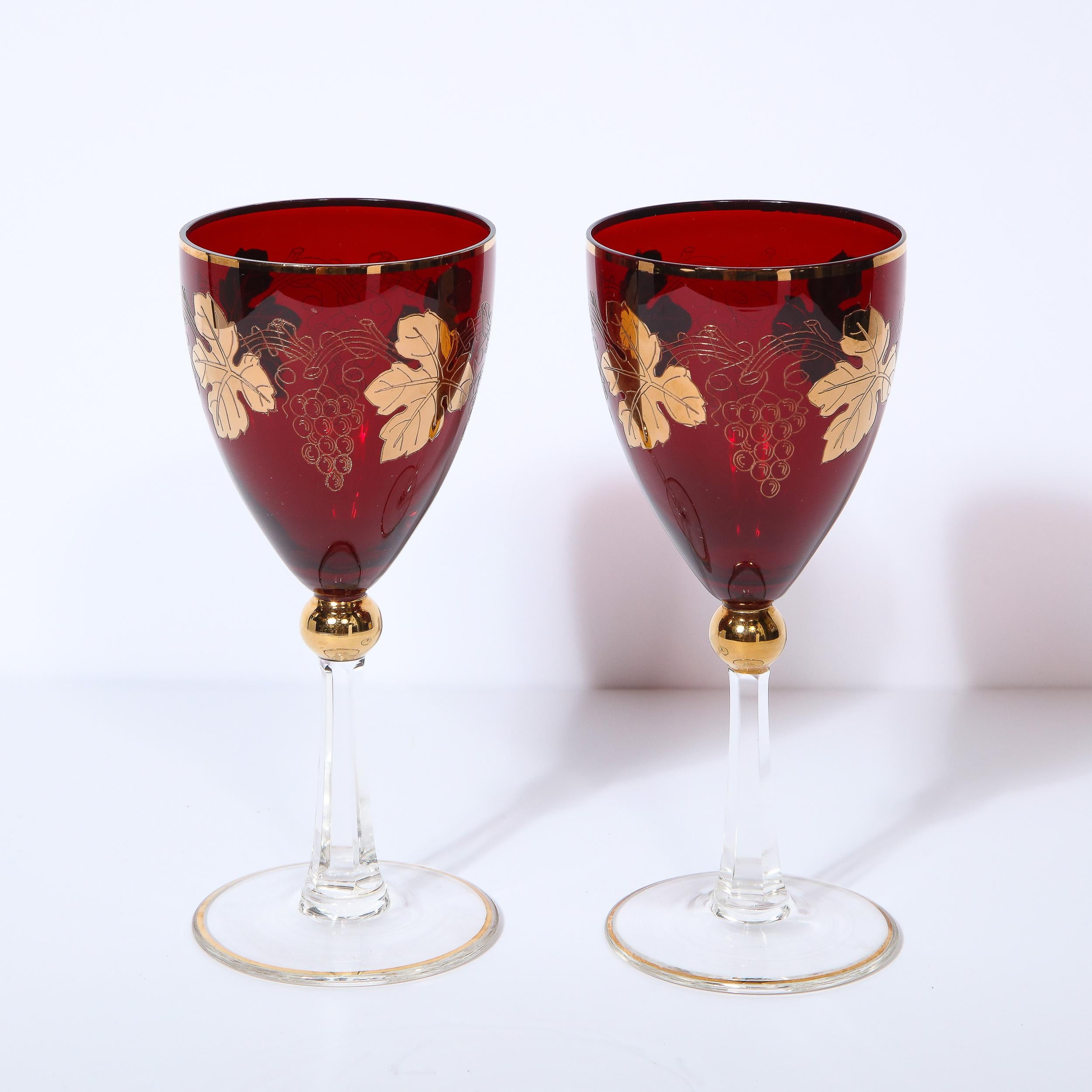 This stunning set of eight Art Deco wine glasses were realized in the United States circa 1940. They feature circular bases and faceted stems in translucent glass capped with spherical embellishment overlaid in 24kt gold. The chalice is fabricated