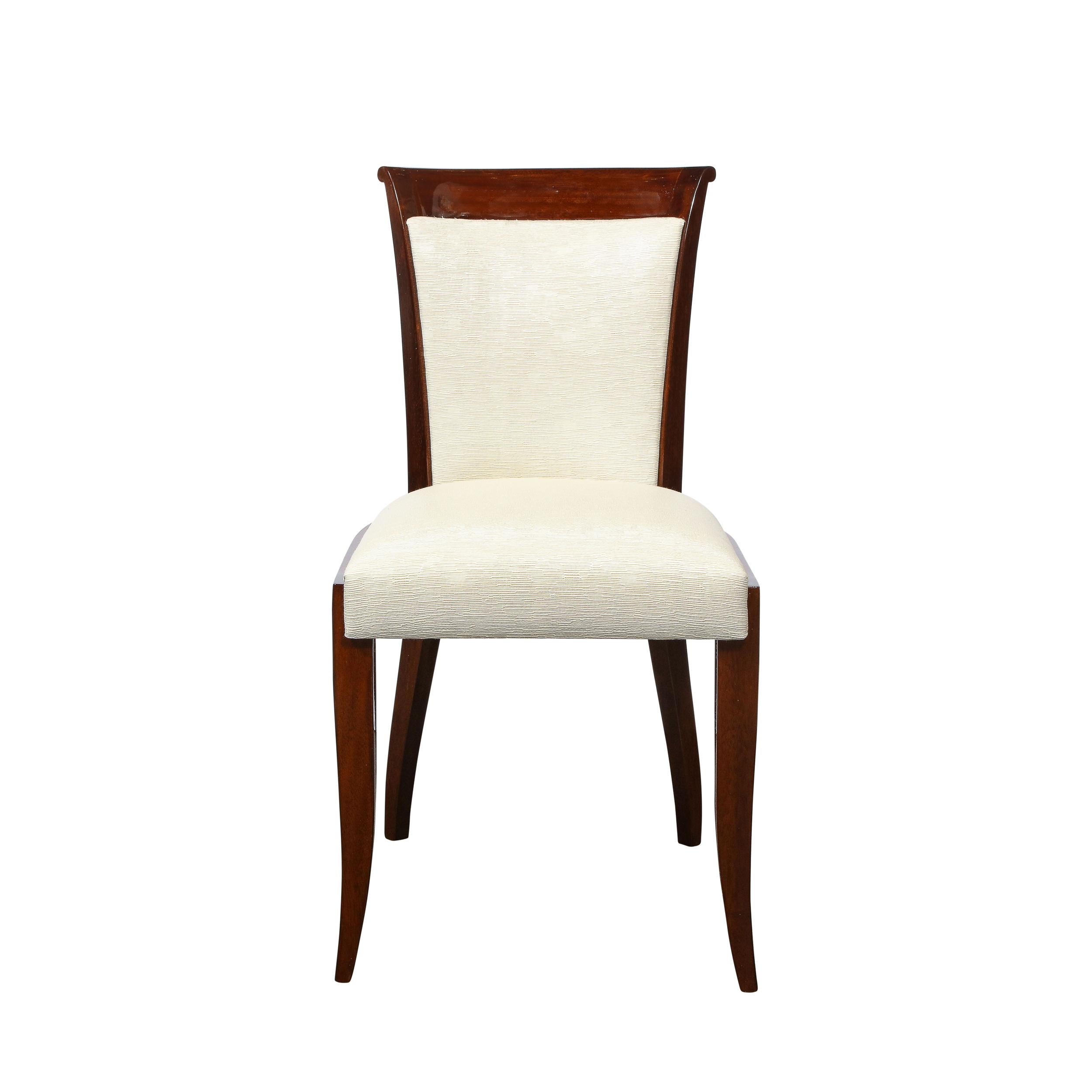 This elegant set of eight Art Deco dining chairs were realized in France circa 1930. They feature walnut frames with subtle hour back form backs with slightly cantilevered tops; stylized klismos style feet; and newly upholstered backs and seats in