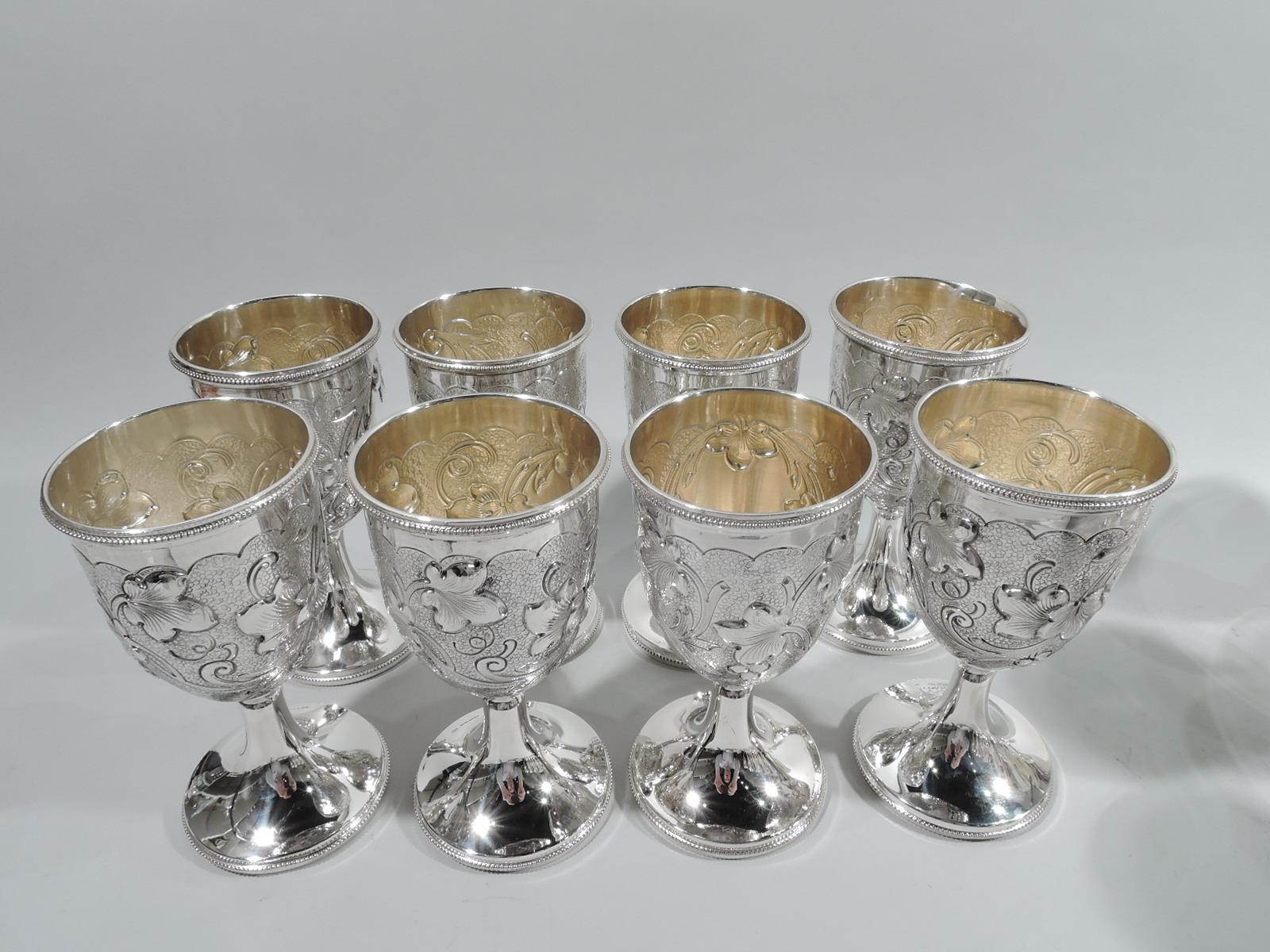Set of 8 Austrian Art Nouveau 935 silver goblets. Each: Oval bowl with chased and engraved flowers on cloud-style ground between plain scallop (top) and spikey (bottom) borders; oval frame (vacant). Plain stem on raised foot. Beading. Interior
