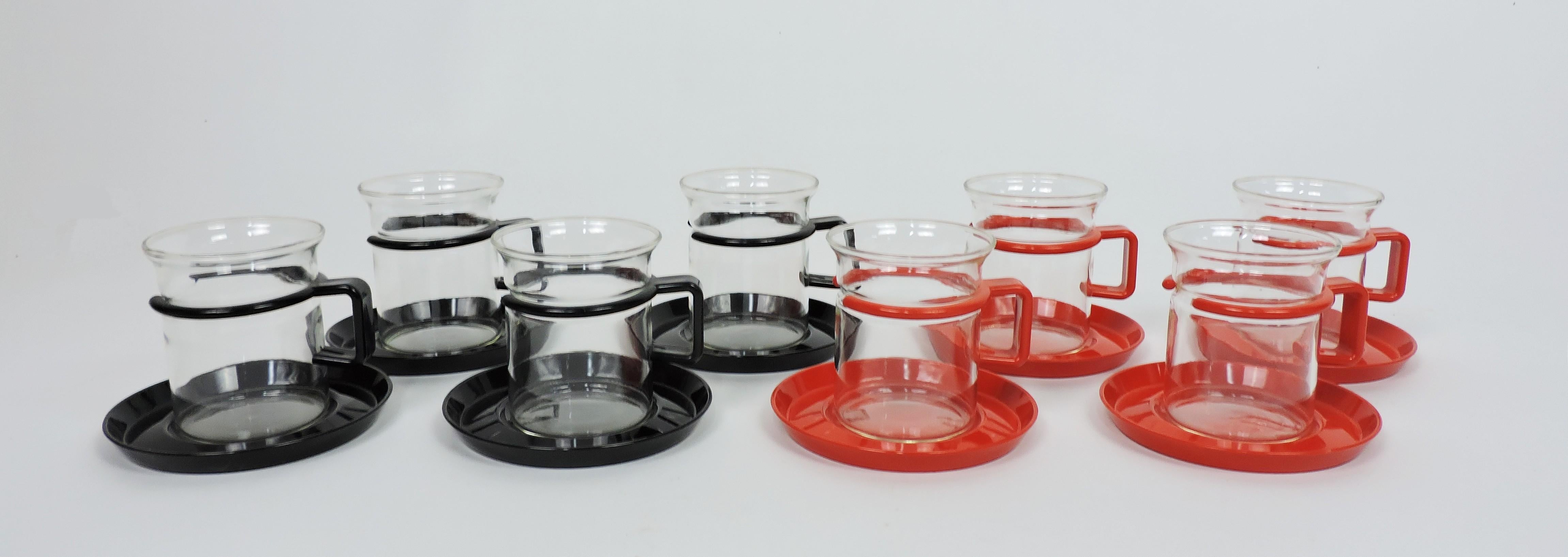 Stylish set of 8 espresso/coffee/tea cups designed in 1974 by Carsten Jorgensen and manufactured in Denmark by Bodum. This set consists of 4 heat resistant tempered glass cups with black plastic handles and matching saucers, and 4 heat resistant