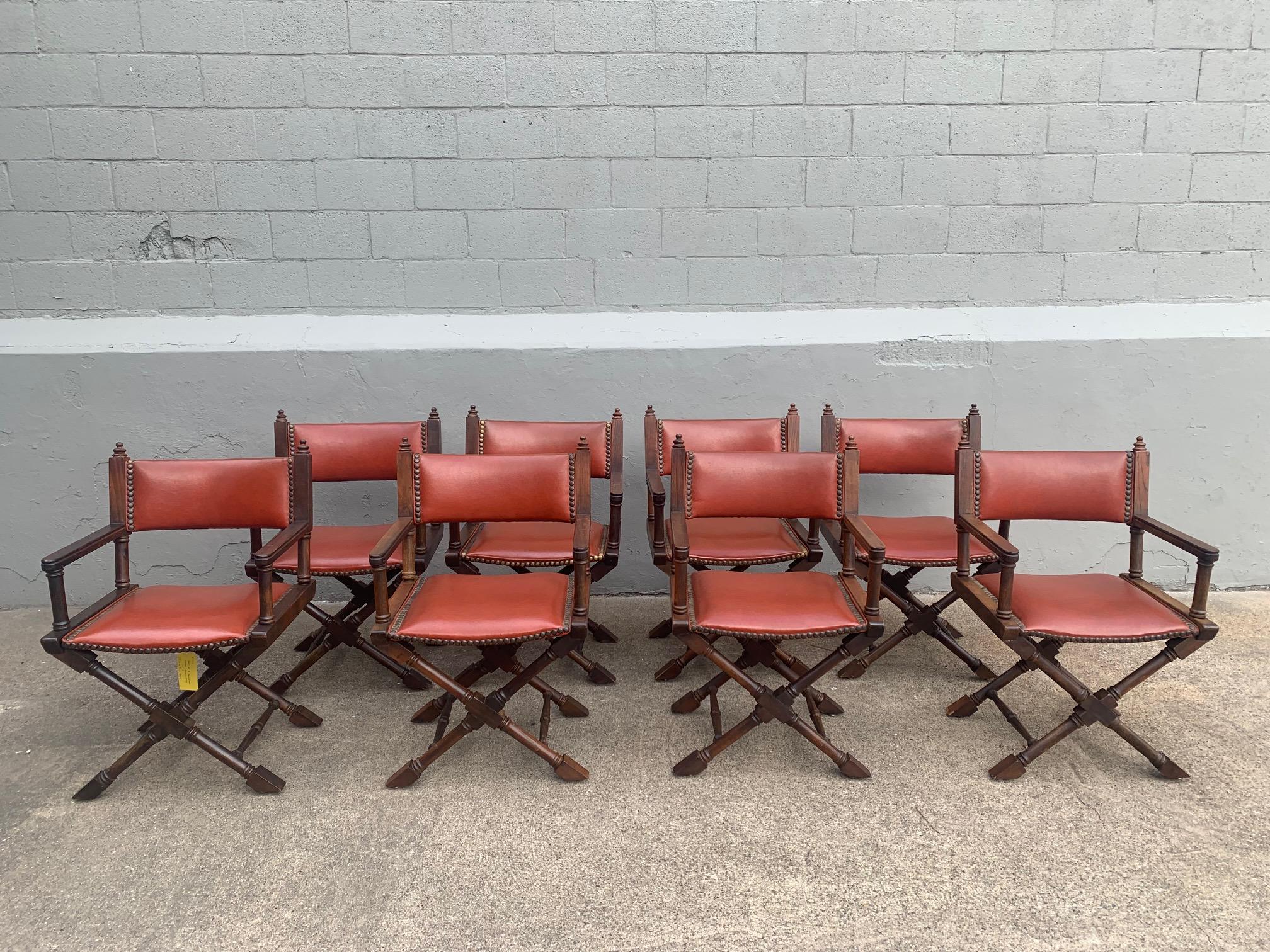 A set of eight American Campaign style wood dining armchair unupolstered in rust colored naugahyde with large nailhead tacks The chairs are large and comfortable and ready to use. The arm height is 26.25