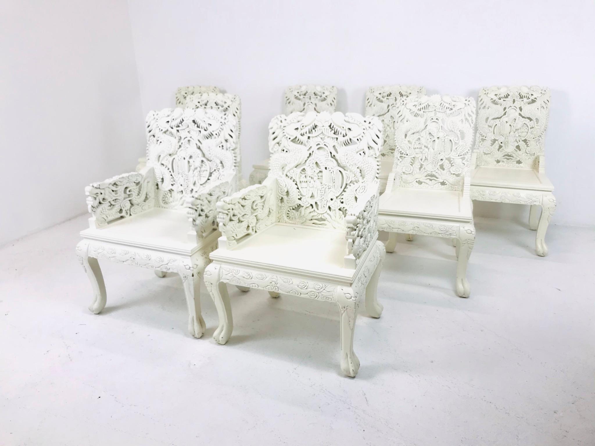 Set of 8 white lacquered Asian dining chairs with pink upholstered seat cushions. Chairs are very heavy and carved from solid teak. 2 side chairs need replacement cushions.