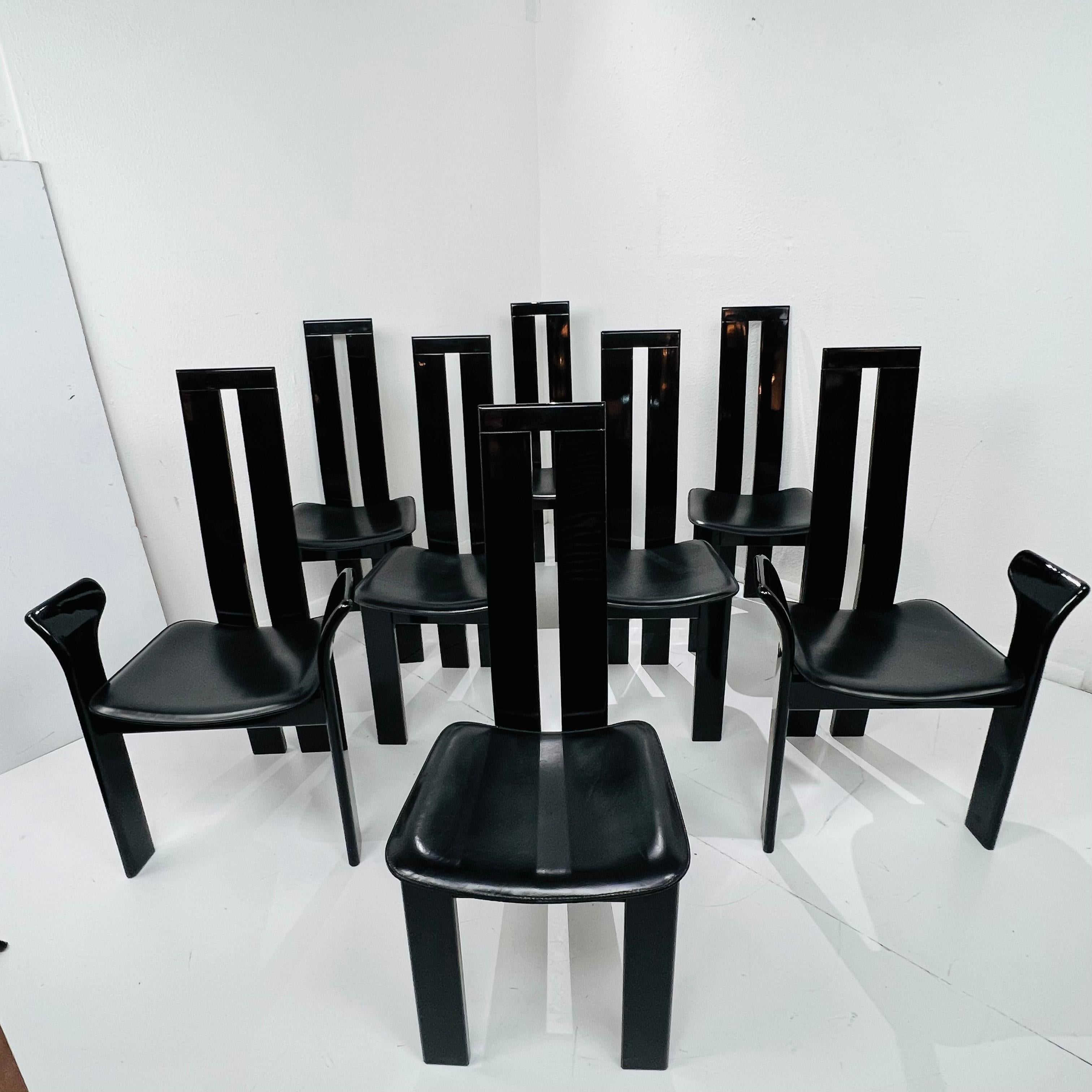 Chic set of post modern dining chairs designed by Pietro Costantini in San Vito al Torre Italy. The iconic chairs feature sculptural style piano black lacquered frames with conforming black leather seat pads. The set consists of six side chairs and