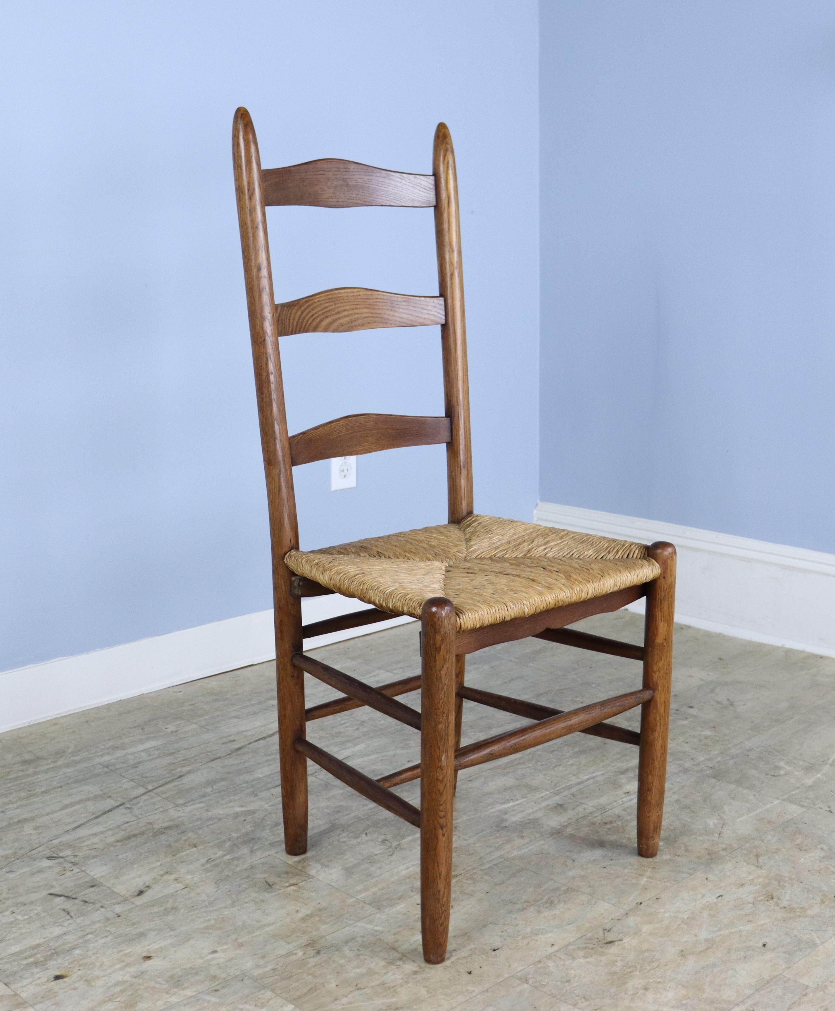 A set of 8 charming English oak ladderback chairs with their original rush seats in good condition. There is some variation in the wood color and grain, as seen in the silhouette. Although the backs of the chairs are high, the have a slight recline