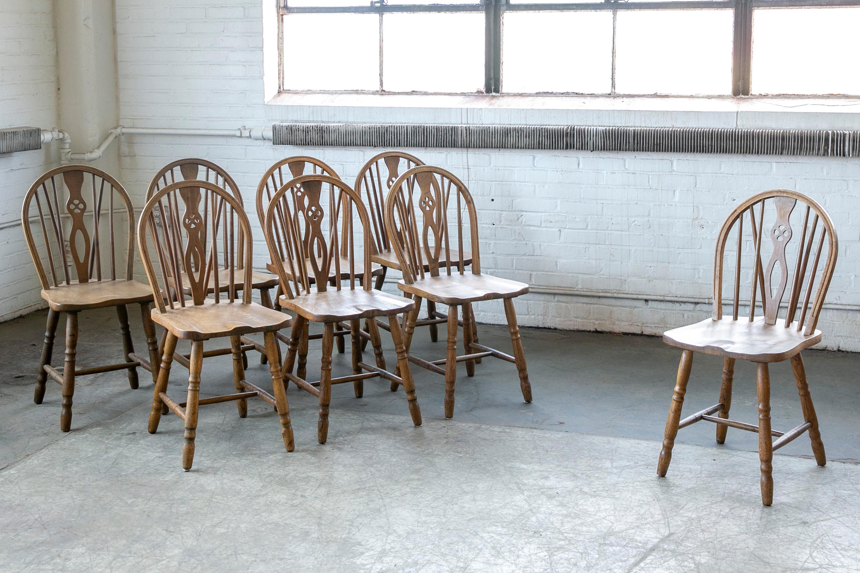Great set of eight Danish dining or kitchen chairs in traditional Windsor style with slat backs and saddle-style seating. All 8 are side chairs. Made from dark stained oak wood probably sometime between 1900 and 1950 in Denmark based on wood type,