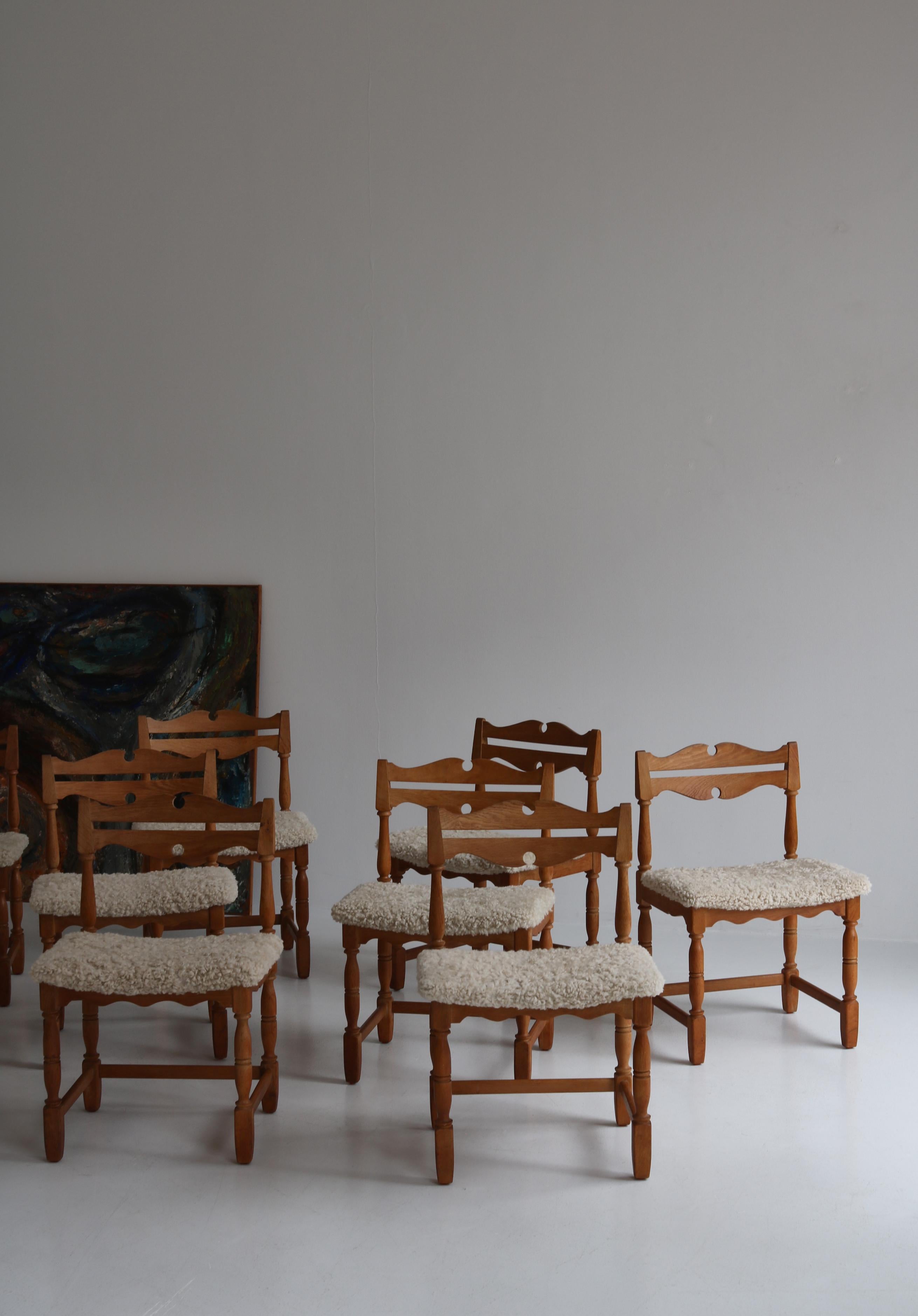 Set of 8 vintage dining chairs in solid patinated Scandinavian oak and reupholstered in sheepskin. This model was designed in the 1960s and is ascribed to Danish designer Henry Kjærnulf. This set was manufactured by the 