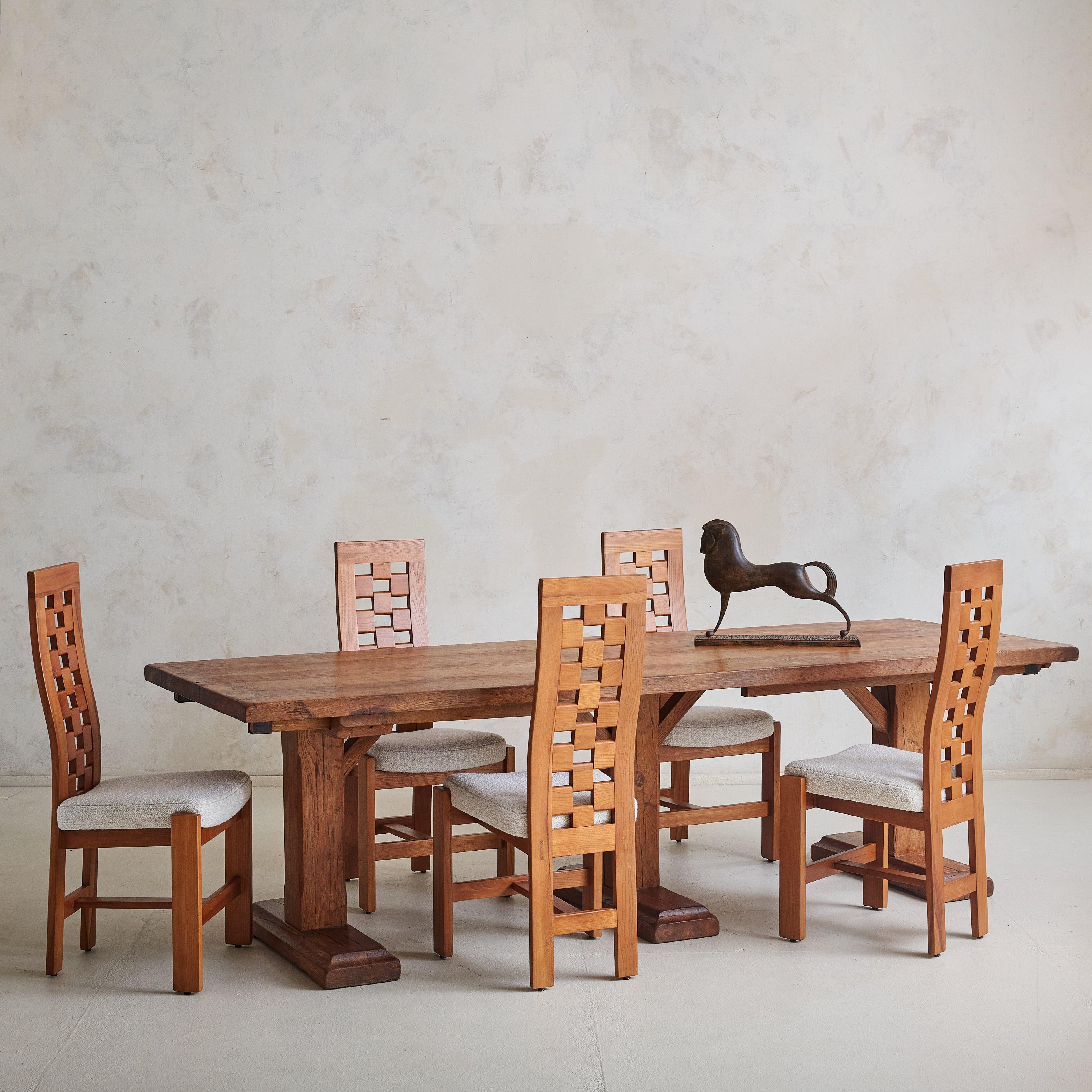 Ensemble de 8 chaises de salle à manger françaises des années 1970, attribuées à Maison Regain. Les cadres en orme massif avec des pieds anguleux et des châssis centraux ancrent le design, tandis que les dossiers présentent un motif à carreaux