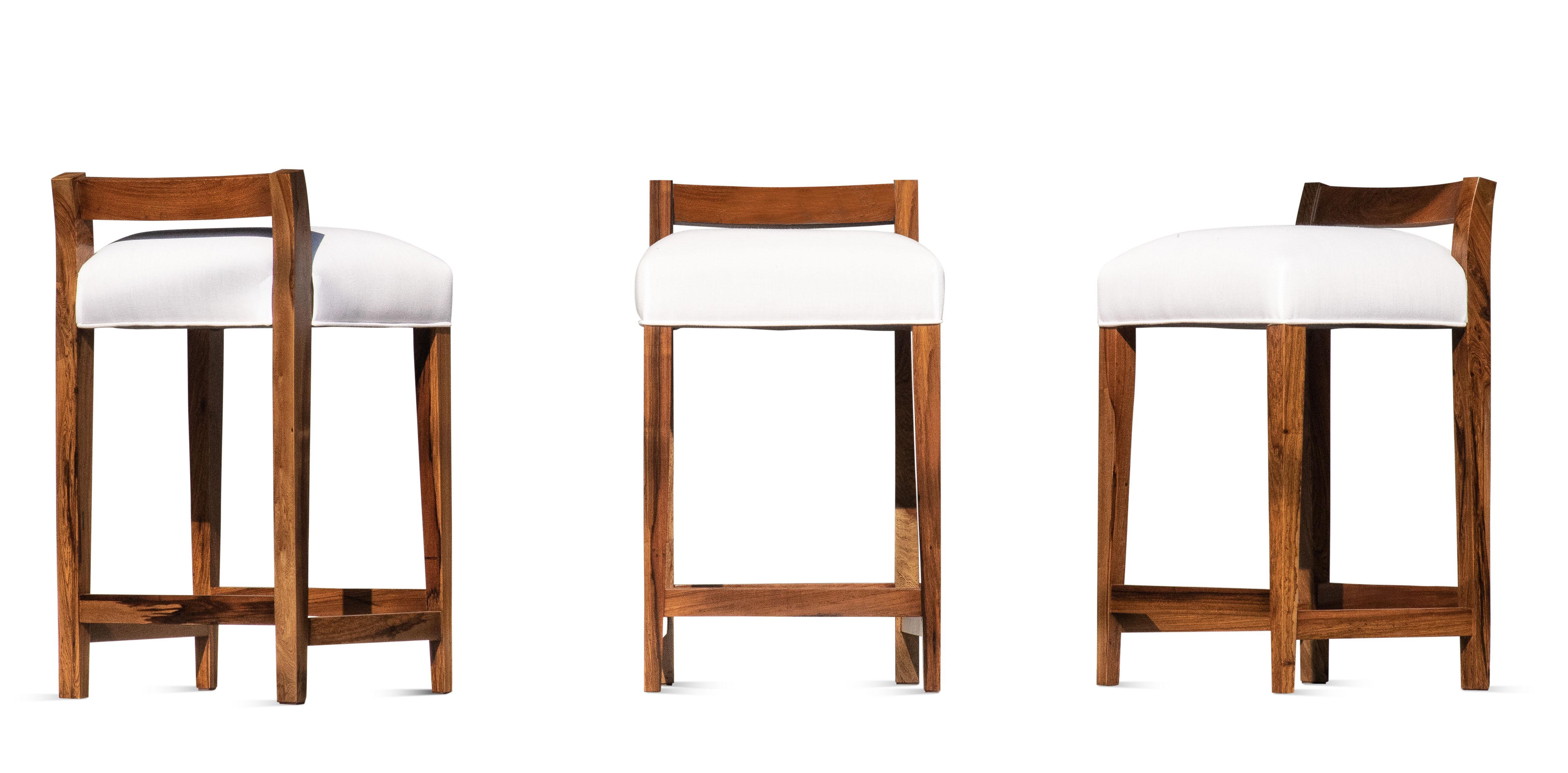 Le tabouret de comptoir Umberto est l'un des sièges originaux les plus vendus de Costantini. Il se caractérise par un dossier moderne et bas en bois massif sculpté et une assise serrée. Disponible dès à présent, tel qu'illustré, en coton blanc ou