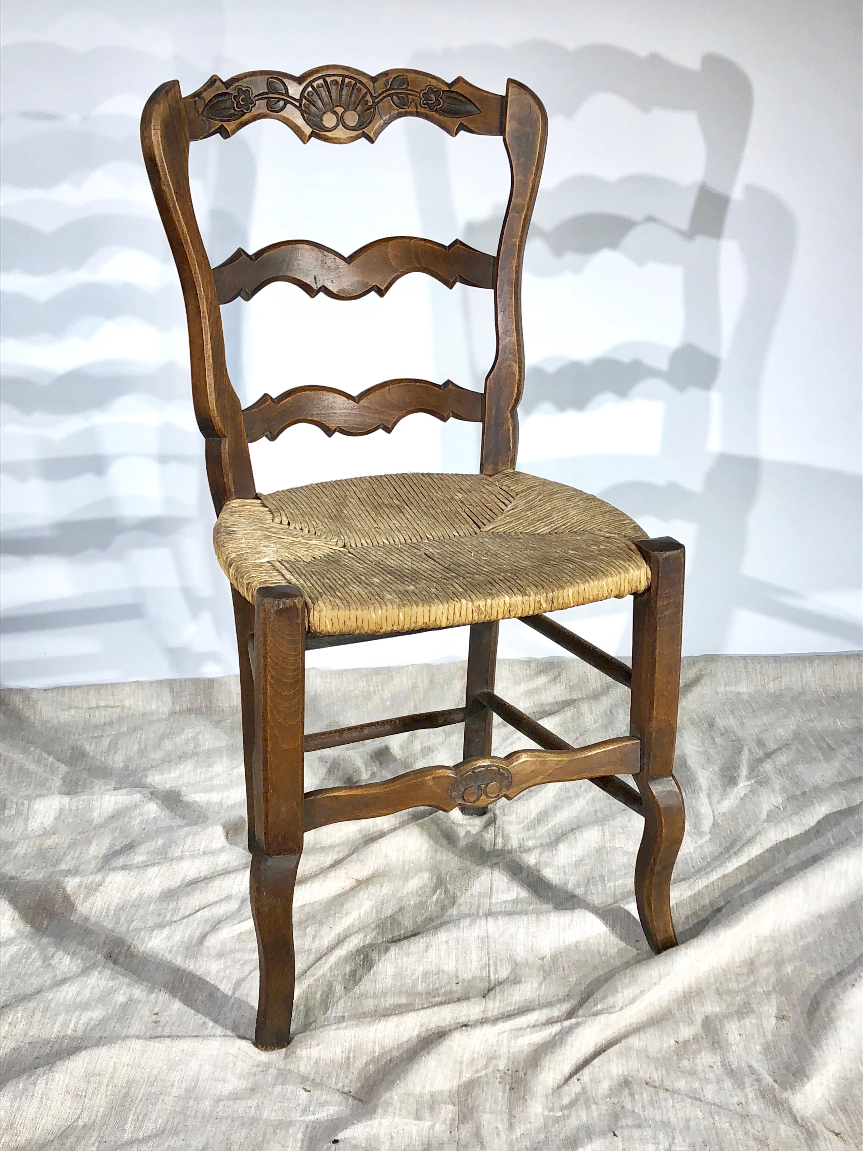 A nice set of 8 ladder-back French County dining chairs, with rush seats and carved back and seat rails, circa 1900. Walnut and oak. 
 