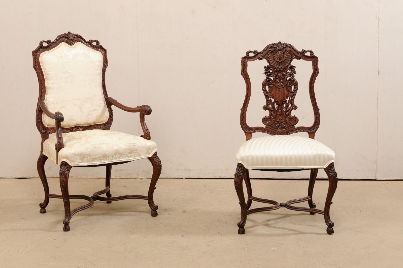 A French set of eight carved-wood, shield-shaped back chairs from the mid-20th century. This vintage set of chairs, consisting of a pair of arm chairs and six side chairs, feature a elaborately carved wood frames and shield-shaped backs. The side