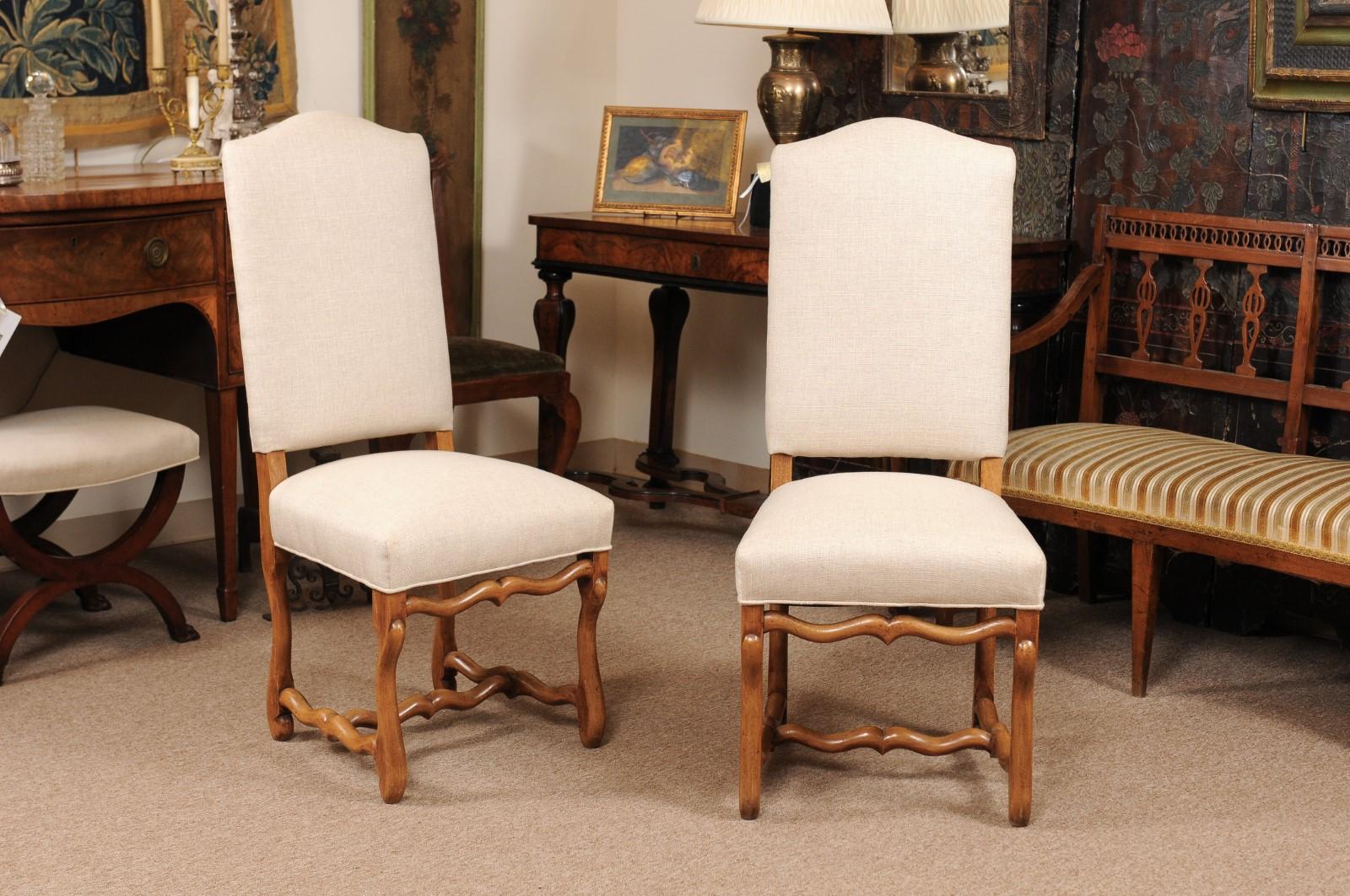 The set of 8 French Louis XIV style dining chairs in beechwood with high arched backs, linen upholstery, button bone legs and stretcher.