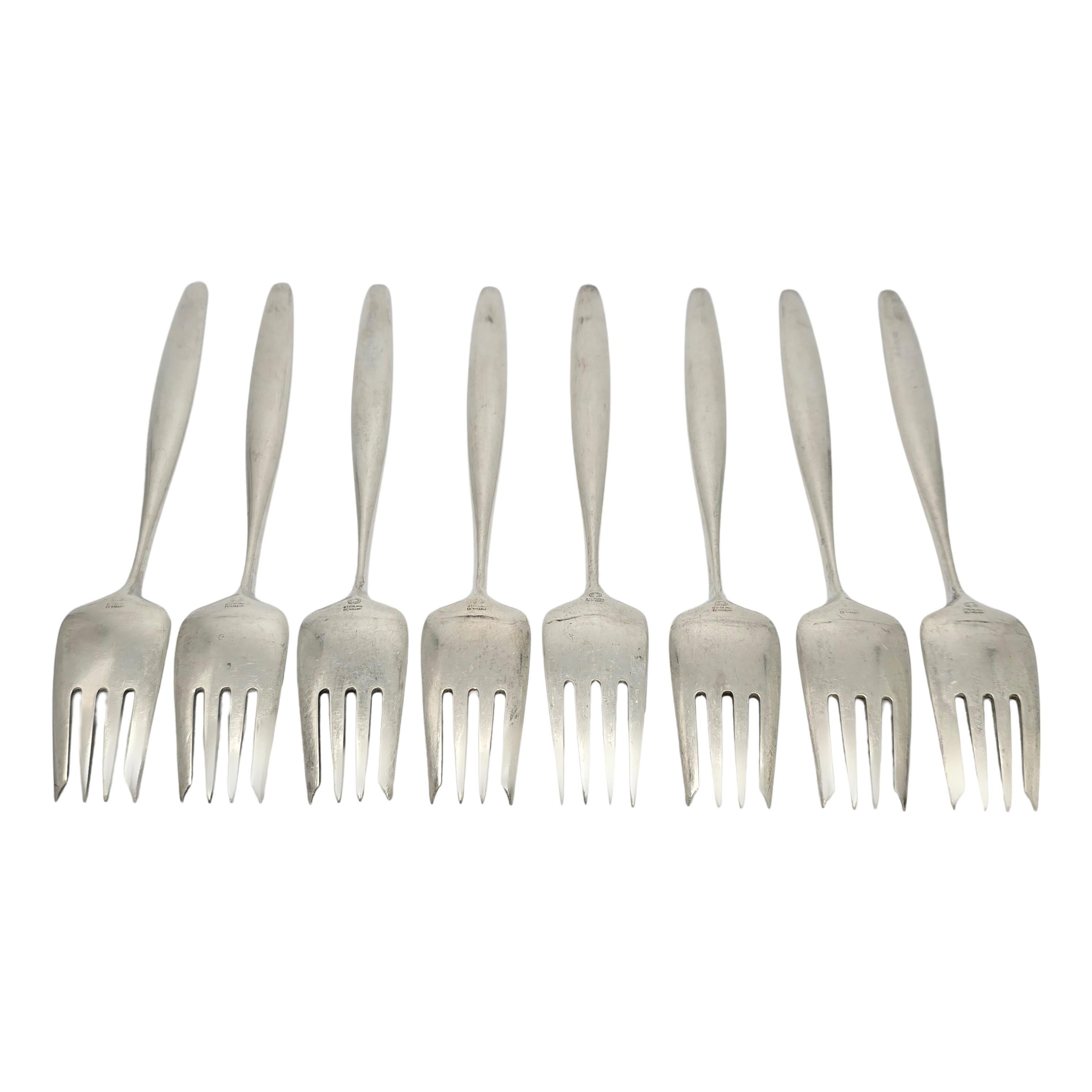 Set di 8 forchette da insalata in argento sterling di Georg Jensen Denmark con motivo Cypress.

Creato da Tias Eckhoff, vincitore di un concorso di design per commemorare il 50° anniversario di Georg Jensen Silversmith nel 1953. Questo modello