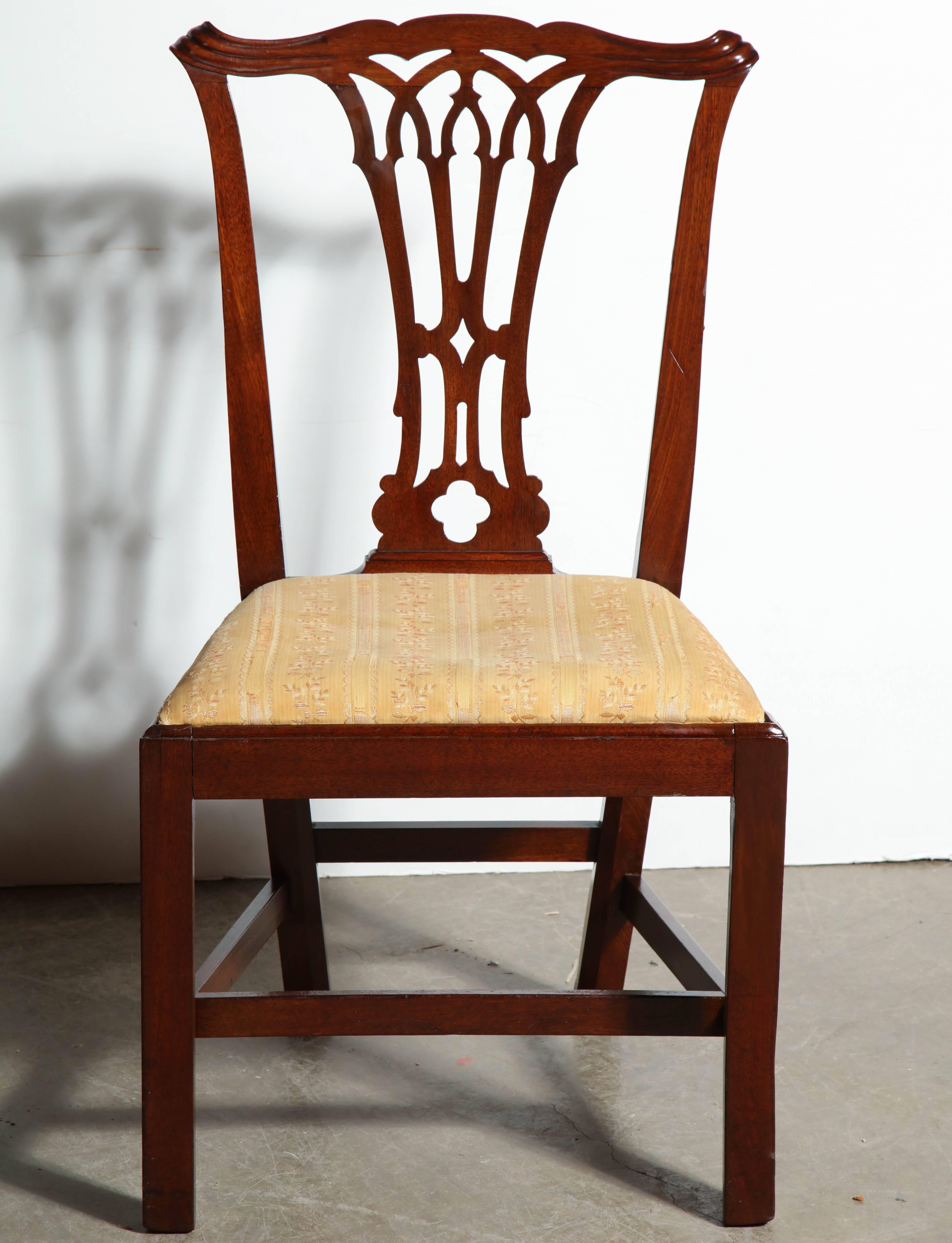 A set of English George III mahogany dining chairs with slip seats, scrolled ears, interlaced splats and a stretcher base.