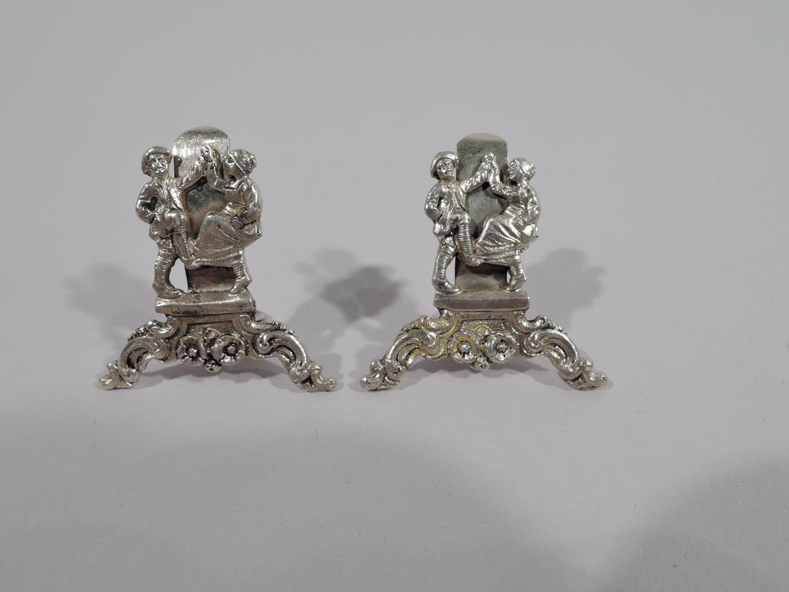 German sterling silver place card holders. This set comprises 8 holders in 3 designs. One holder features an elegant courtly couple executing a cozy minuet. Three holders feature spirited country jiggers. Four holders feature entwined Bacchic babes,