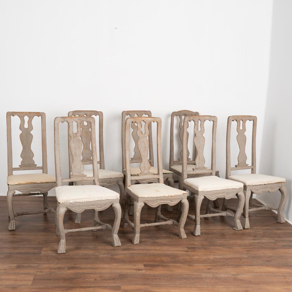 Antique set of eight Swedish country baroque dining side chairs with tall backs. 
Gray painted finish is distressed, revealing the natural wood patina below. 
Muslin/linen seats show old staining, simply tacked down creating a deconstructed look.