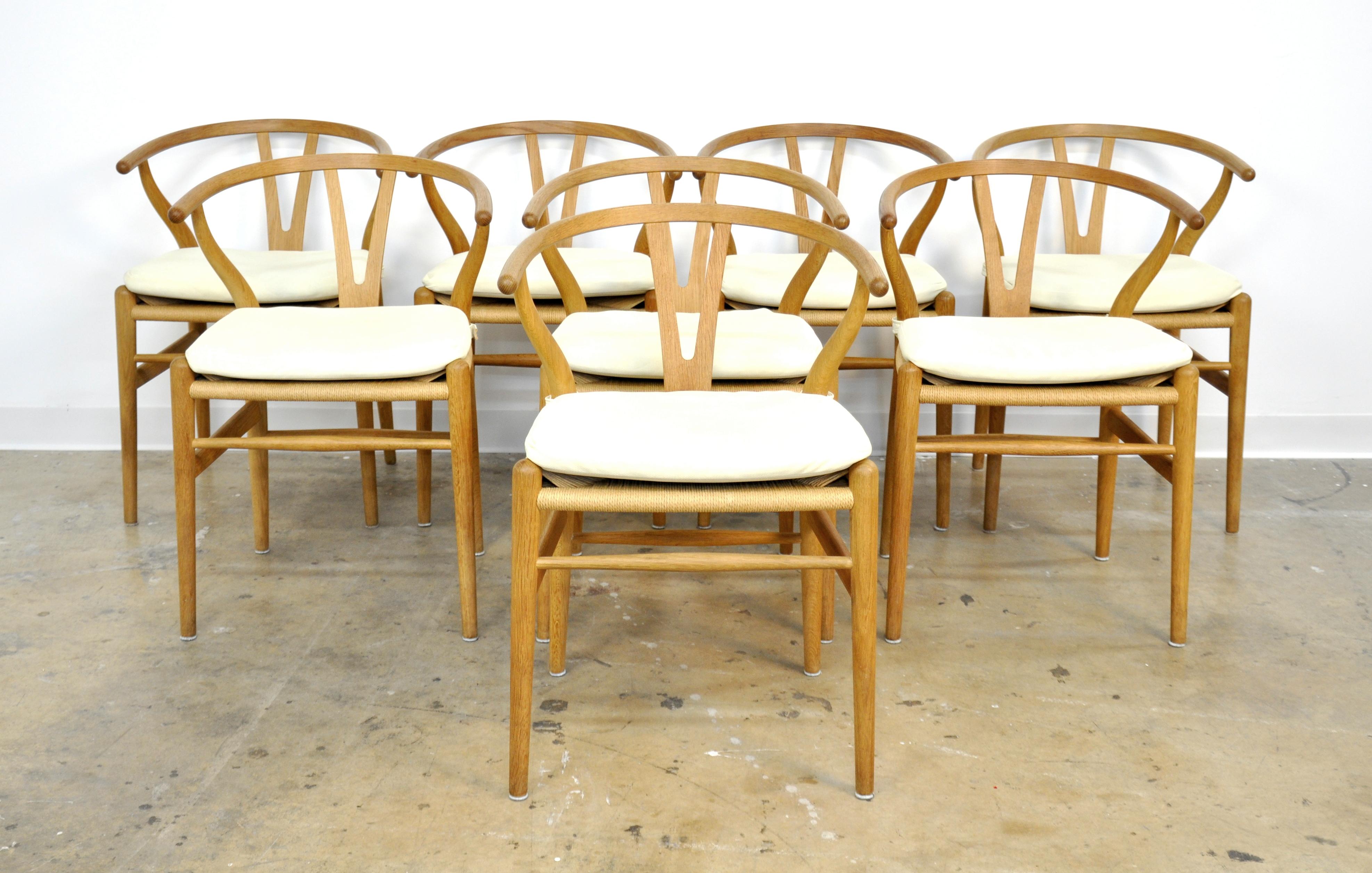 A set of eight vintage Mid-Century Modern CH24 dining chairs, also known as Y chair, designed by Hans Wegner in 1949, and in continuous production by Carl Hansen since 1950. The sculptural oak armchairs feature a steam-bent solid wood frame and a