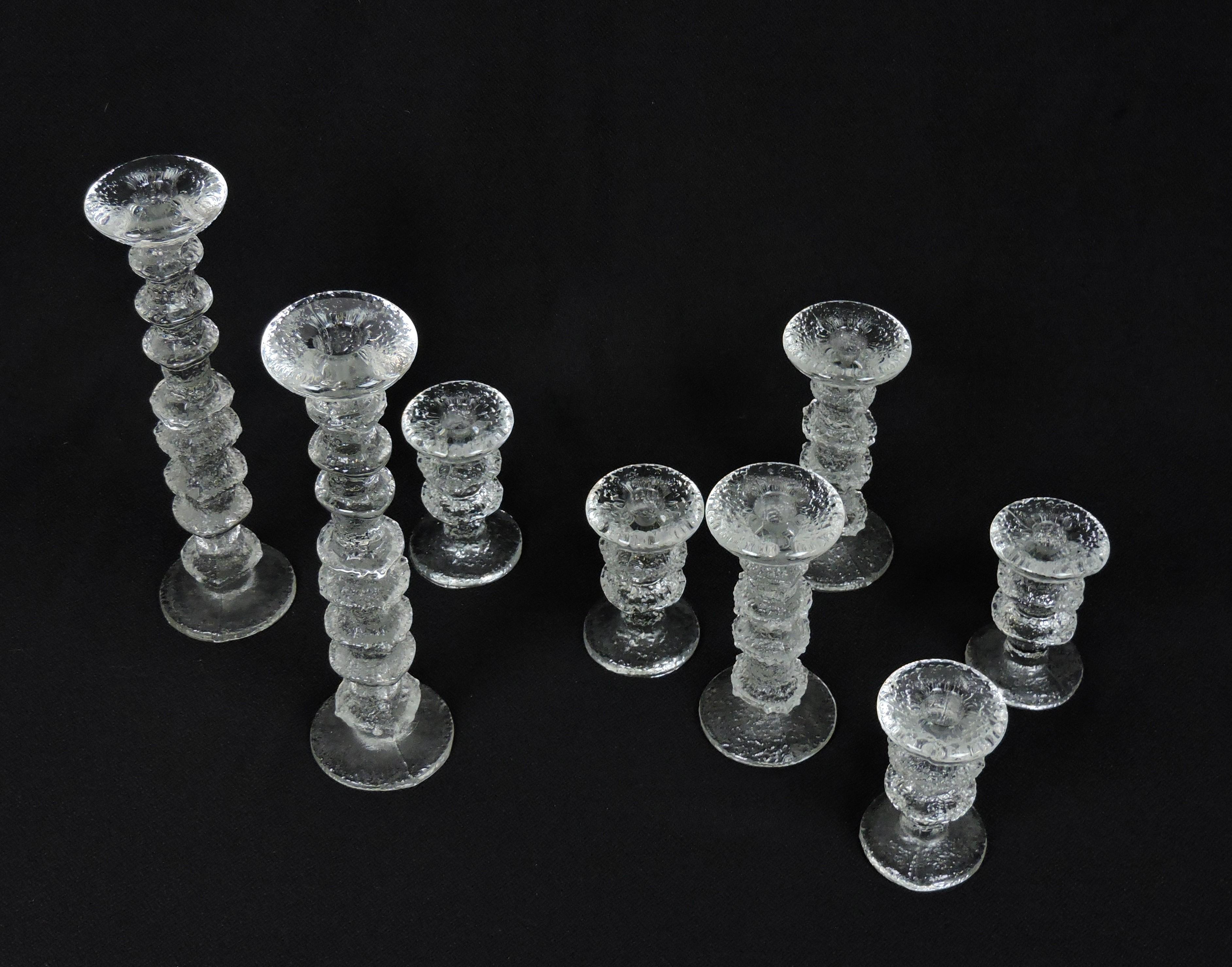 Beautiful set of 8 Festivo glass candlesticks designed by Timo Sarpaneva and manufactured in Finland by Iittala. This set includes two 12 5/8 inch tall (8 rings), two 7 1/8 inch tall (4 rings), and four 4 3/4 inch tall (2rings) candle holders.