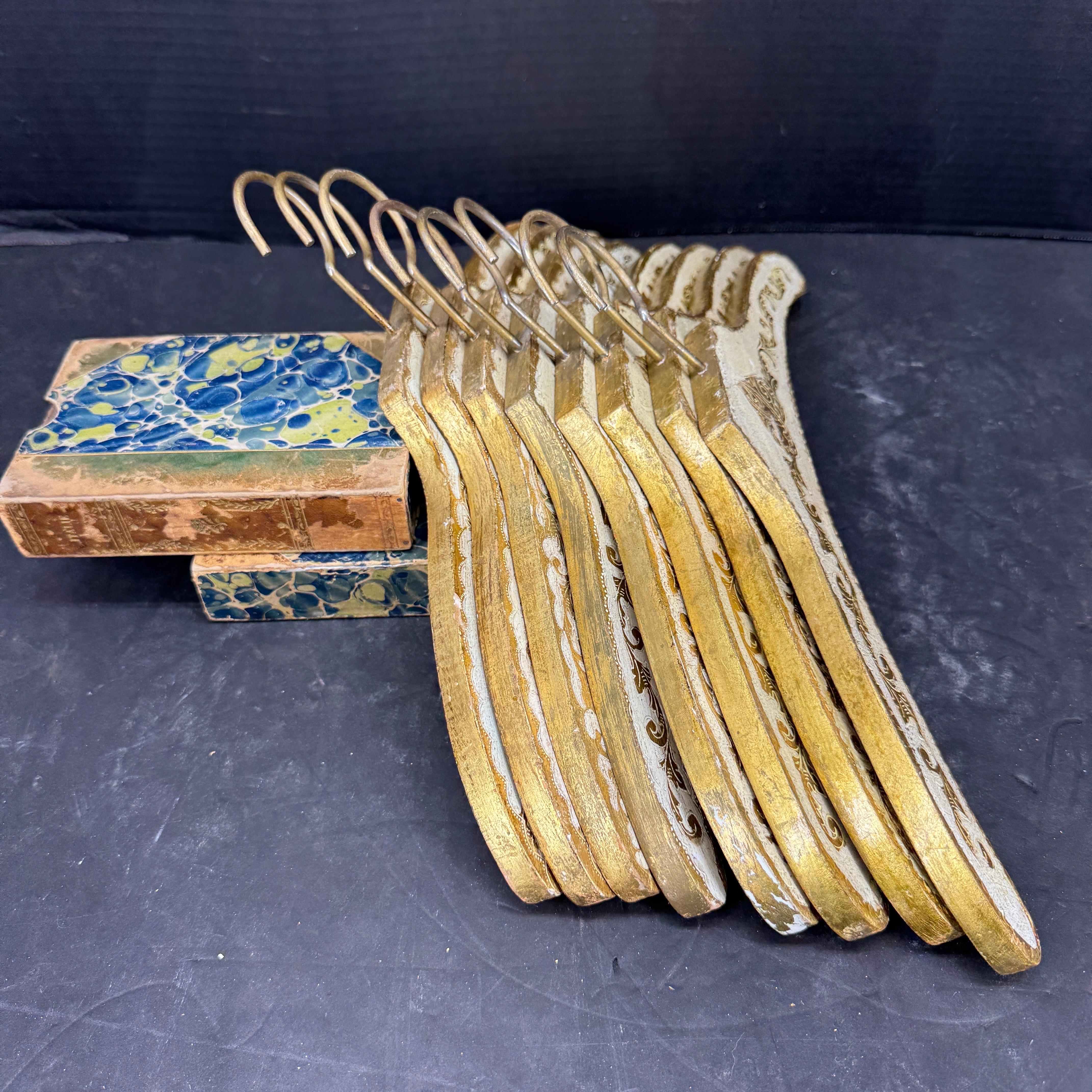 Charming set of vintage cream and gilt gold coat clothing hangers. We have seen these sold individually but to find a set of 8 is rare. As seen in the photos,  this collection features three different center emblems. We see these used to hold some