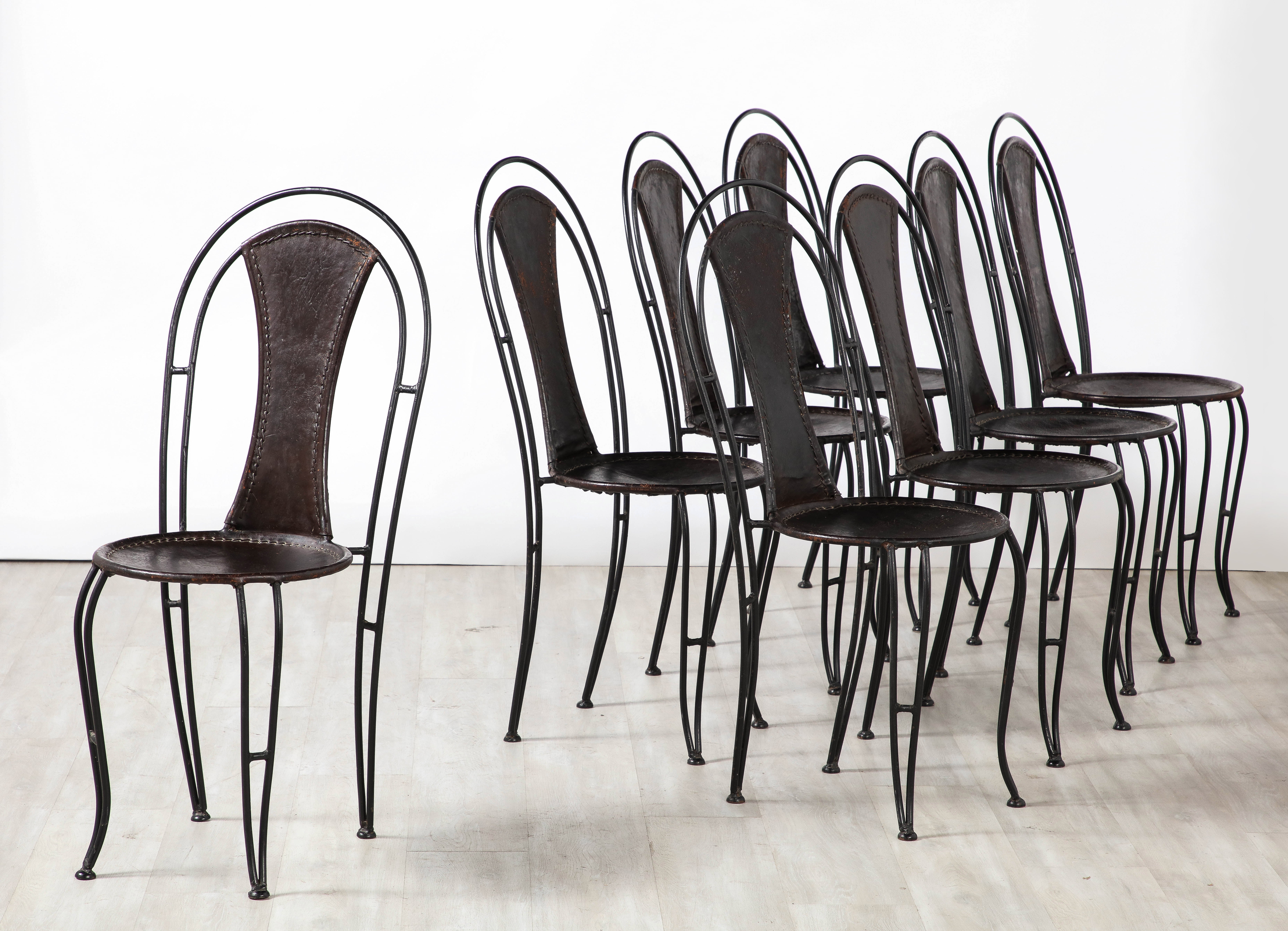 An Italian set of eight black leather and metal bistro chairs/ dining chairs. The chairs are highly sculptural with arched backs, circular seats and fanciful scrolled legs. The black hand-stitched leather is all original, truly beautiful patina.