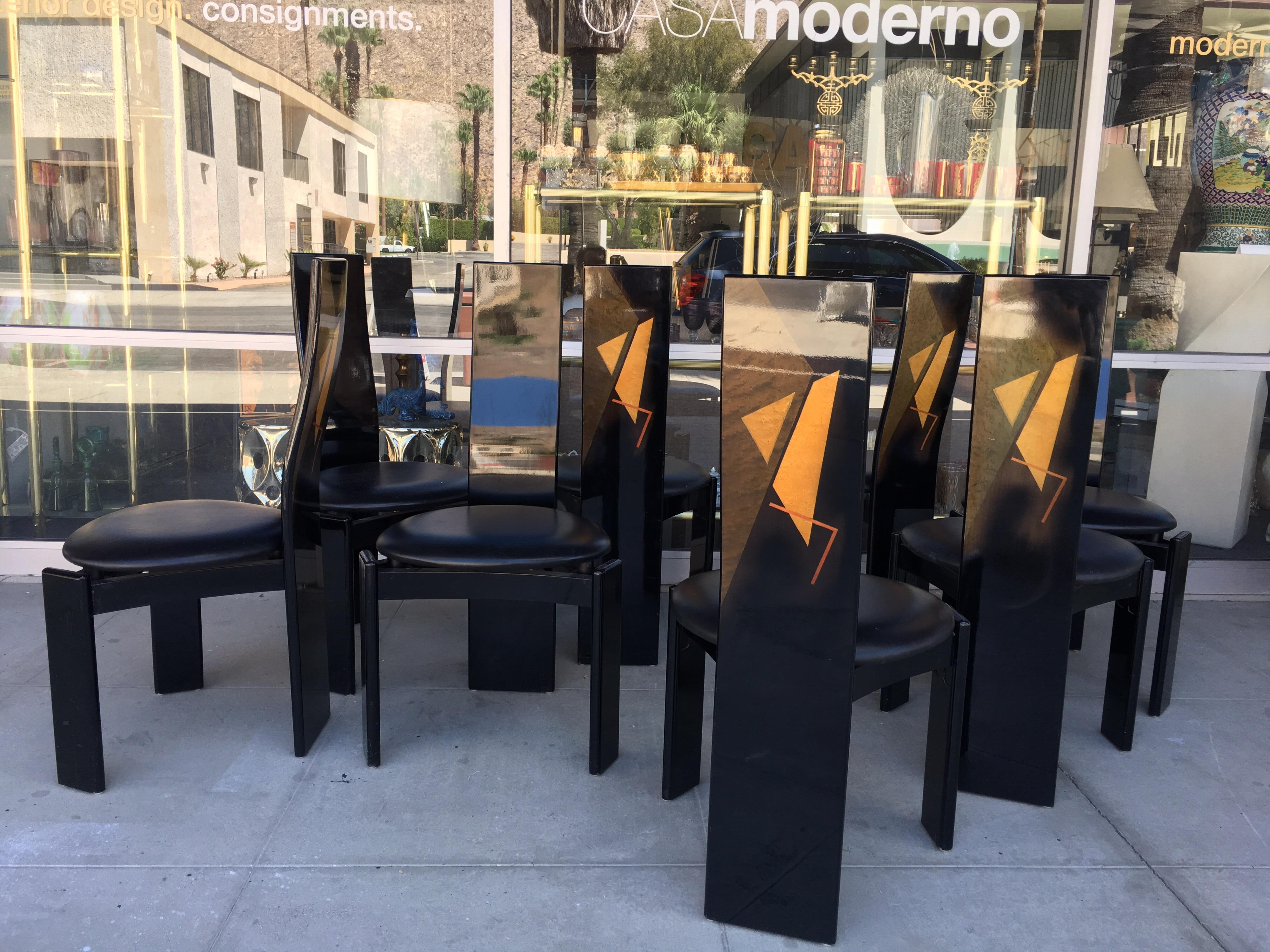 These very chic vintage Italian modern dining chairs were made in the 1980s in a cool Post Modern style at the time of the Memphis craze in Italy. Set of 8 black lacquered wood with painted backs that have a graphic design. Original leather seats