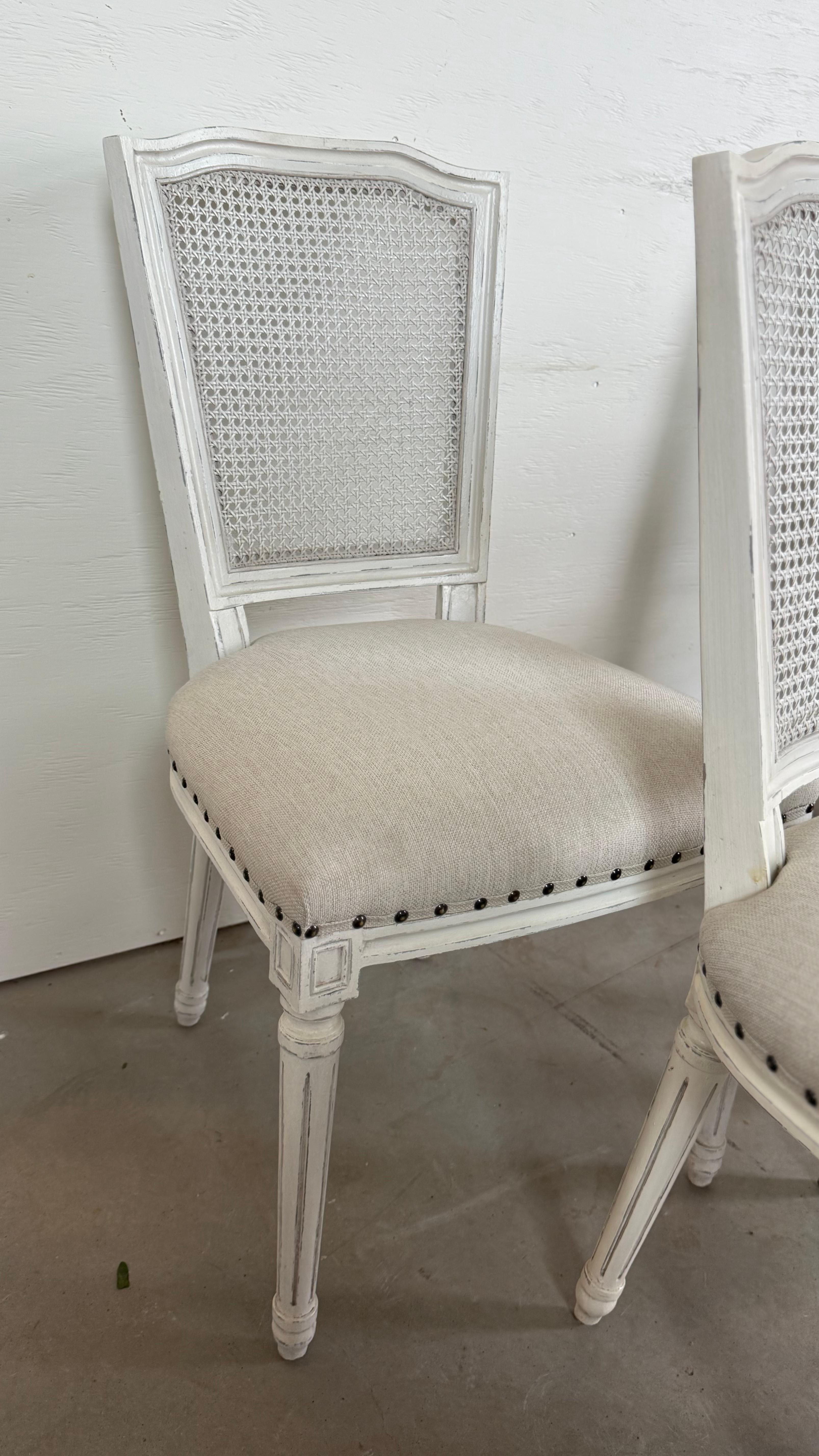 Elegant et intemporel, cet ensemble de huit chaises de salle à manger de style Louis XVI apporte une sophistication française raffinée à la salle à manger moderne. Finie dans un ton blanc doux, chaque chaise présente un dossier classique en rotin et