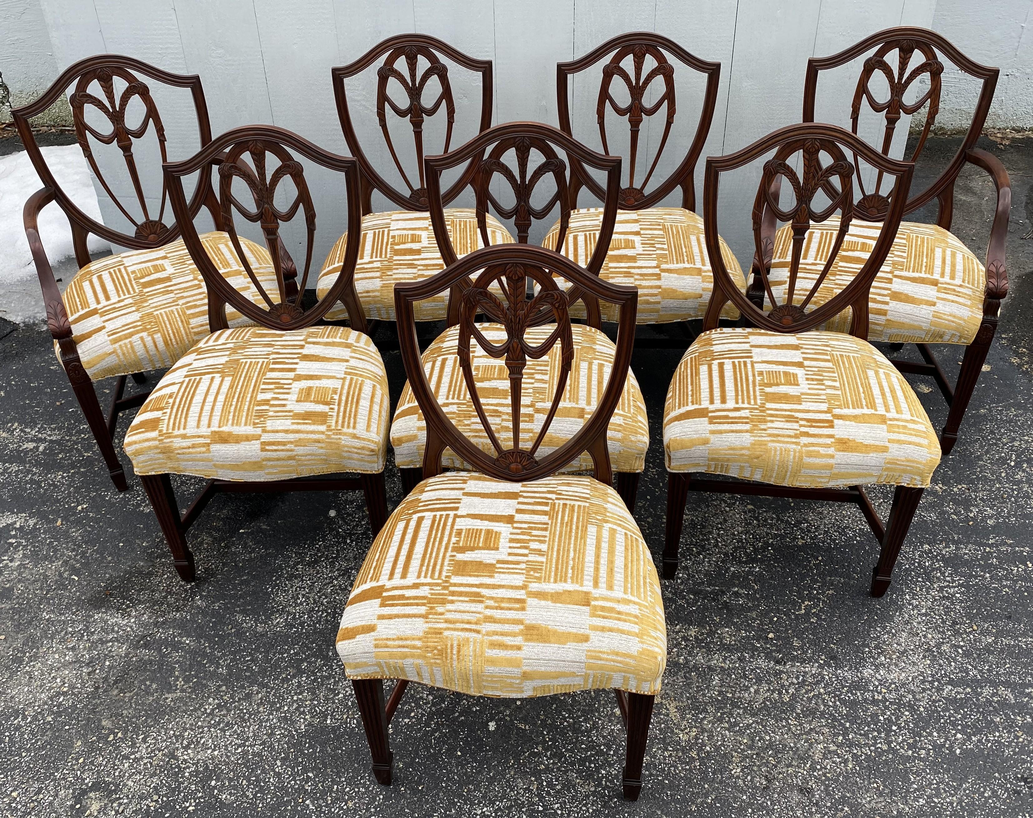 A fine quality set of eight solid foliate carved mahogany shield back dining chairs, two arm chairs and six side chairs, adorned with the Prince of Wales feathers, probably English in origin, with new upholstery, H form stretchers, and carved spade