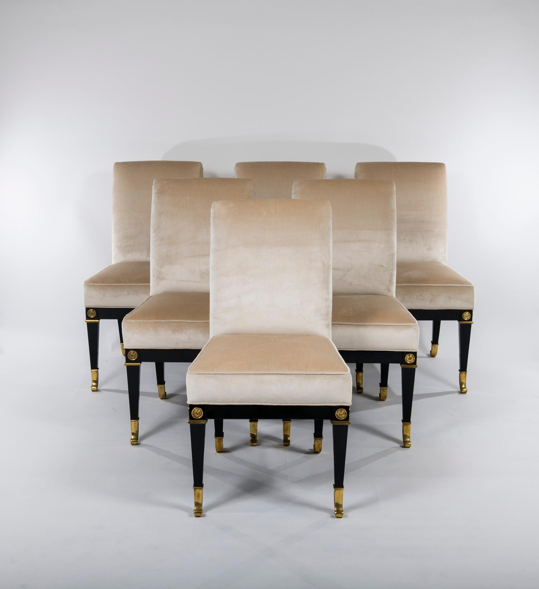 A stunning set of 8 vintage Mastercraft neoclassical style dining chairs. These ebonized chairs with bronze sabots have been newly modified with professionally rebuilt and padded upholstery in a Champagne Donghia silk velvet. 

Dimensions:
Side