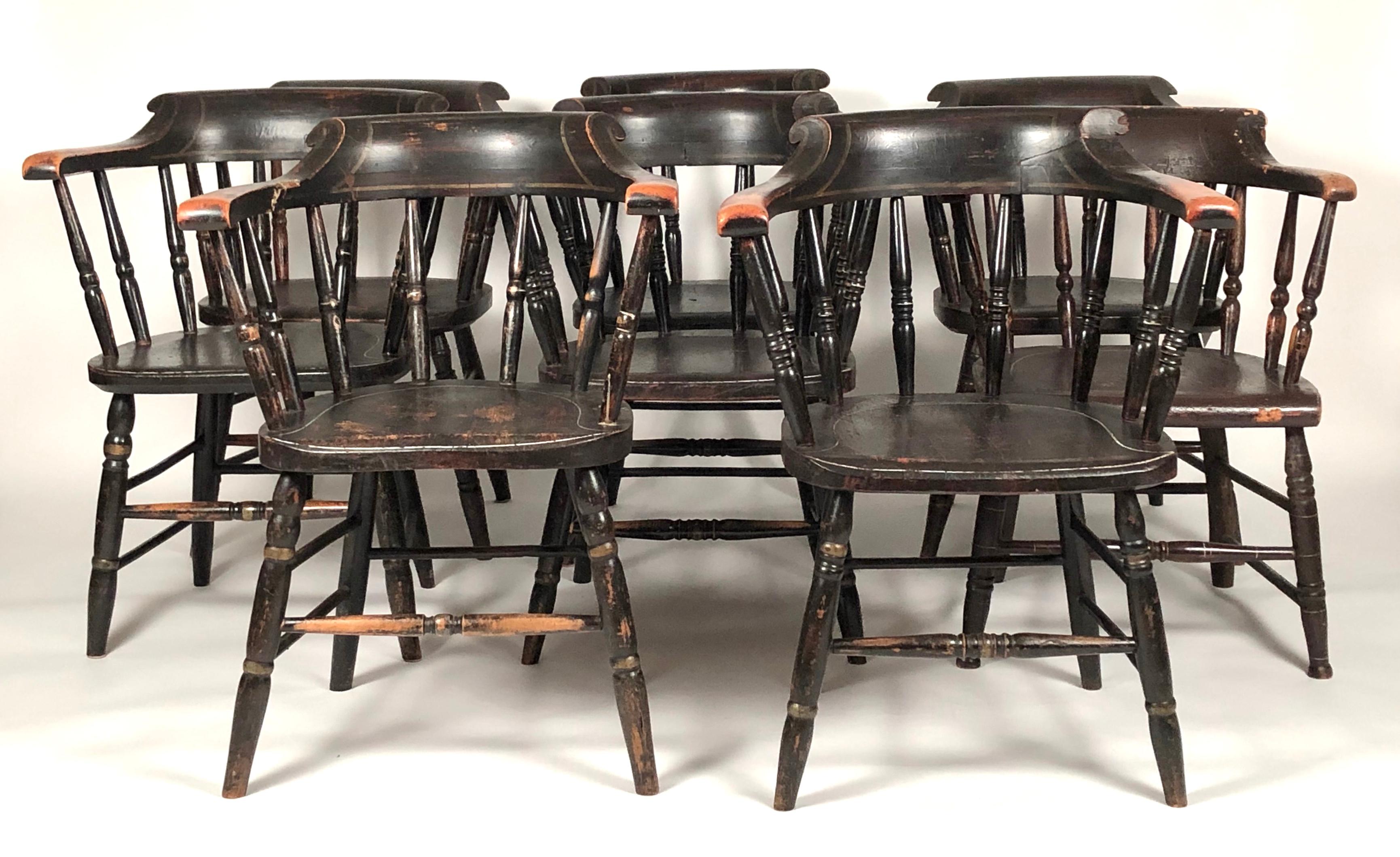 A hard to find matched set of 8 country captain's chairs in their old black paint with pinstripe decoration, each with a curved back supported by turned spindles over a shaped seat supported by turned legs joined by cross stretchers. 7 nearly