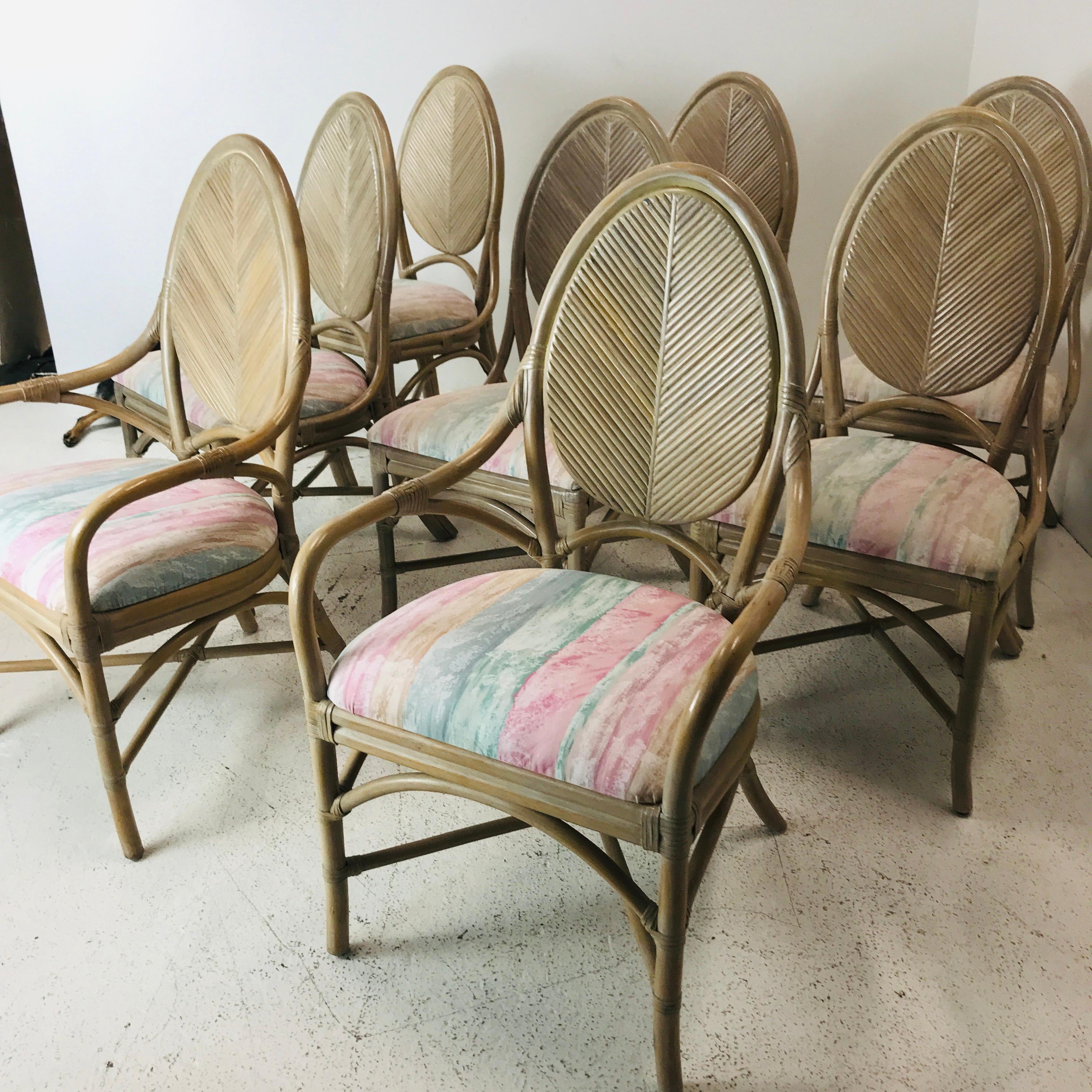 Set of 8 McGuire rattan bistro style dining chairs featuring a distressed lacquer finish with floral upholstery. Includes 2 chairs with arms and 6 side chairs.