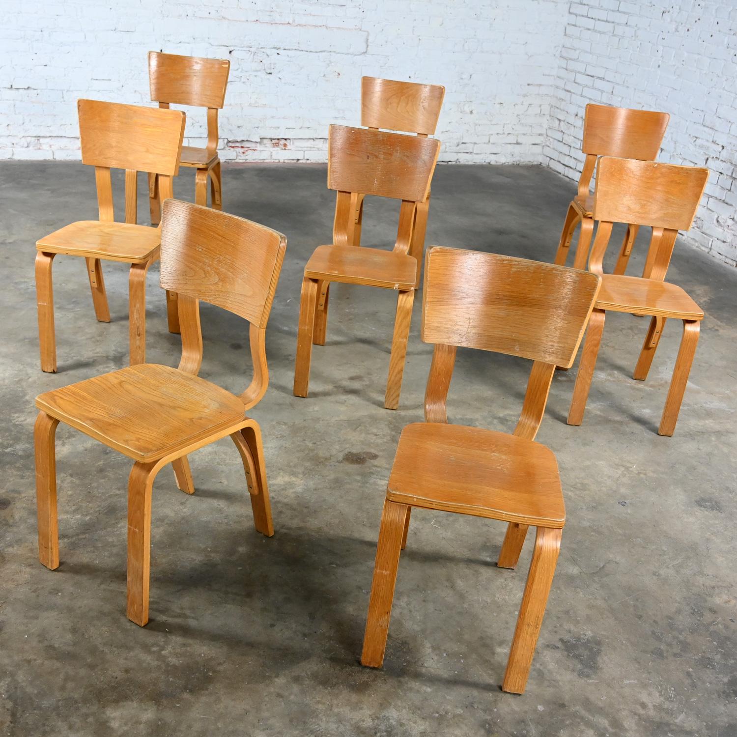 Merveilleuses chaises de salle à manger Thonet #1216-S17-B1 en contreplaqué de chêne courbé avec des sièges en selle et un seul dossier en arc, ensemble de 8. Très bon état, en gardant à l'esprit qu'il s'agit de chaises vintage et non pas neuves et