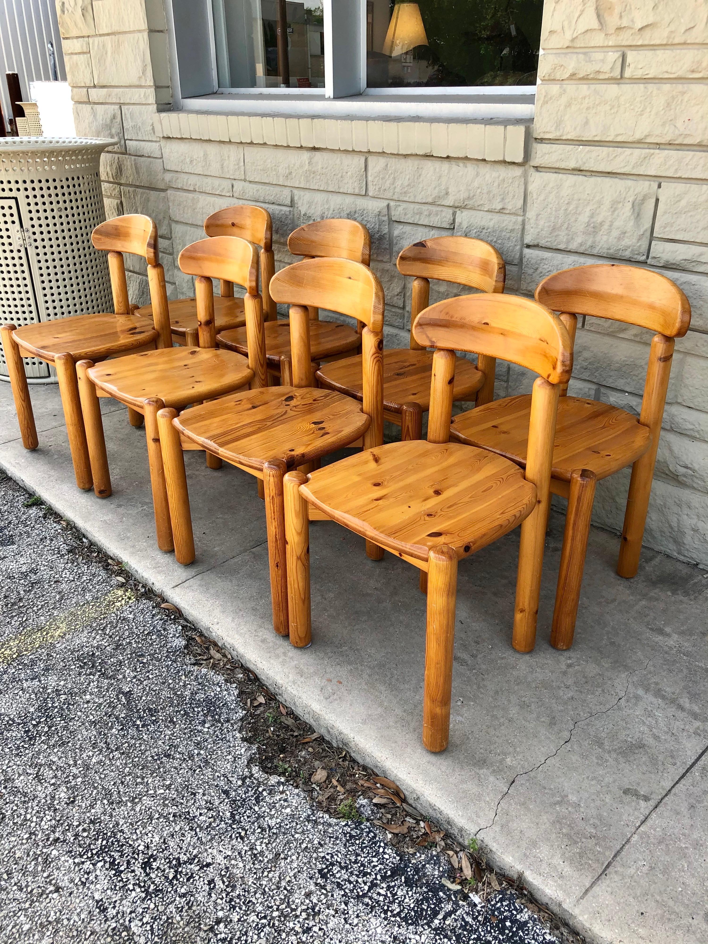 Danish Mid-Century Modern dining chairs in pine designed by Rainer Daumiller have a carved seat and backrest. Rainer's designs were sculptural as well as functional. The set of 8 dining chairs are in good condition' wear is consistent with age.