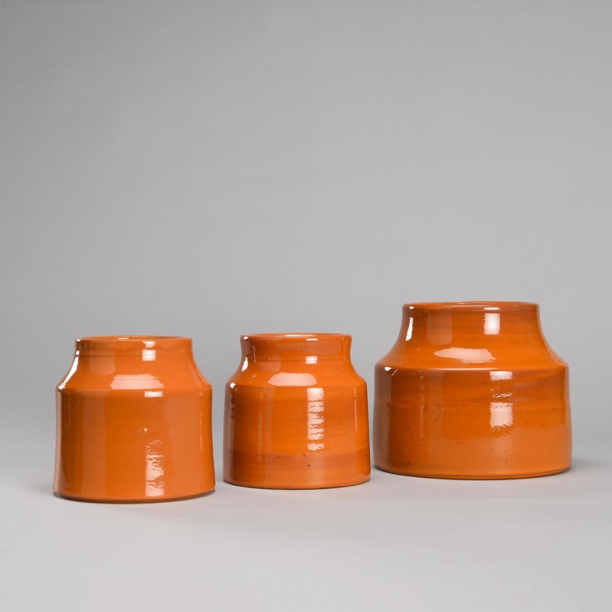 Set of 8 glazed ceramic cylindrical jars with tightened necks with a beautiful orange enamel with their original label 