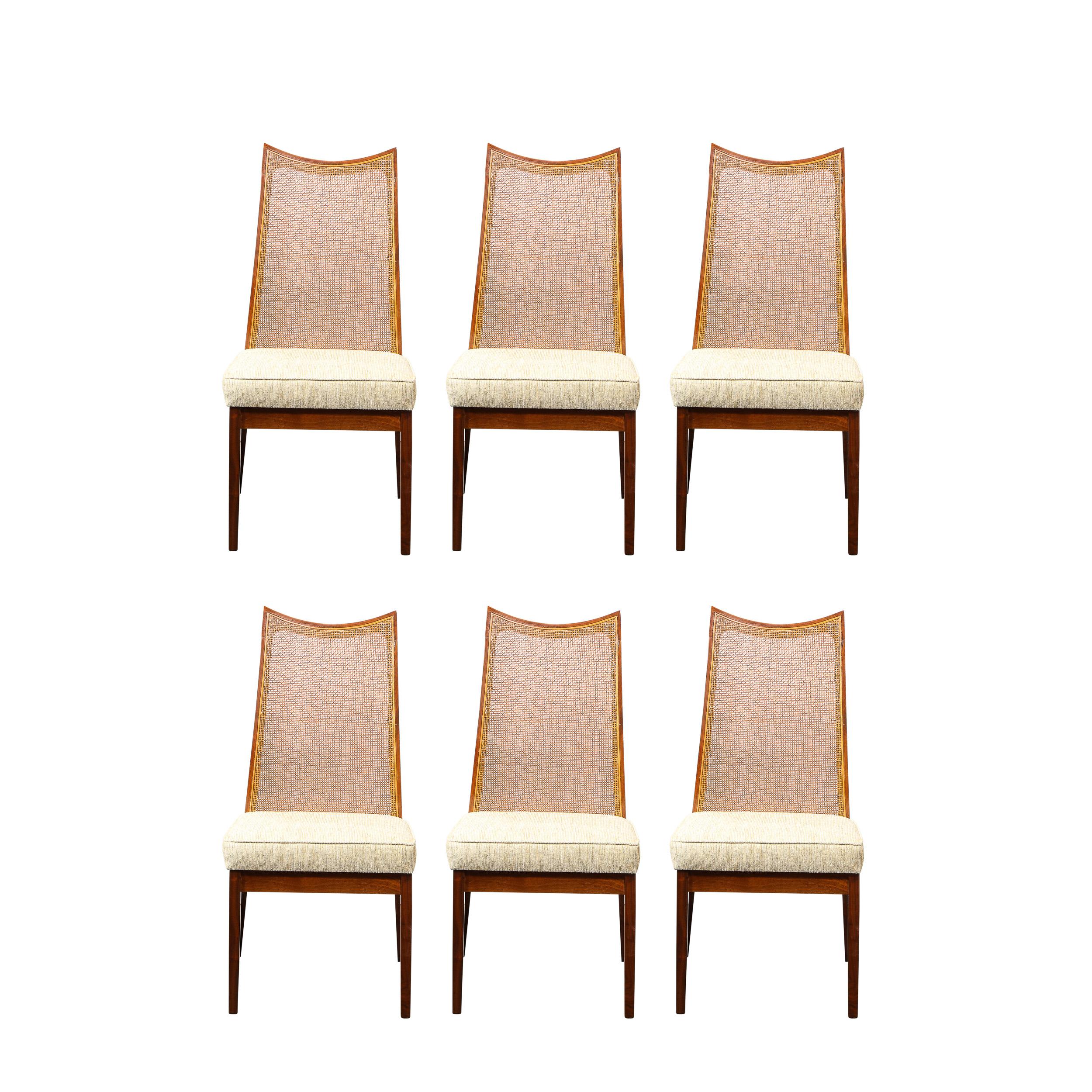 This stunning set of eight Mid Century Modern dining chairs were realized by the esteemed maker John Stuart Inc, in the United States circa 1960. The set features two arm chairs and six side chairs. The chairs offer hand rubbed bookmatched walnut