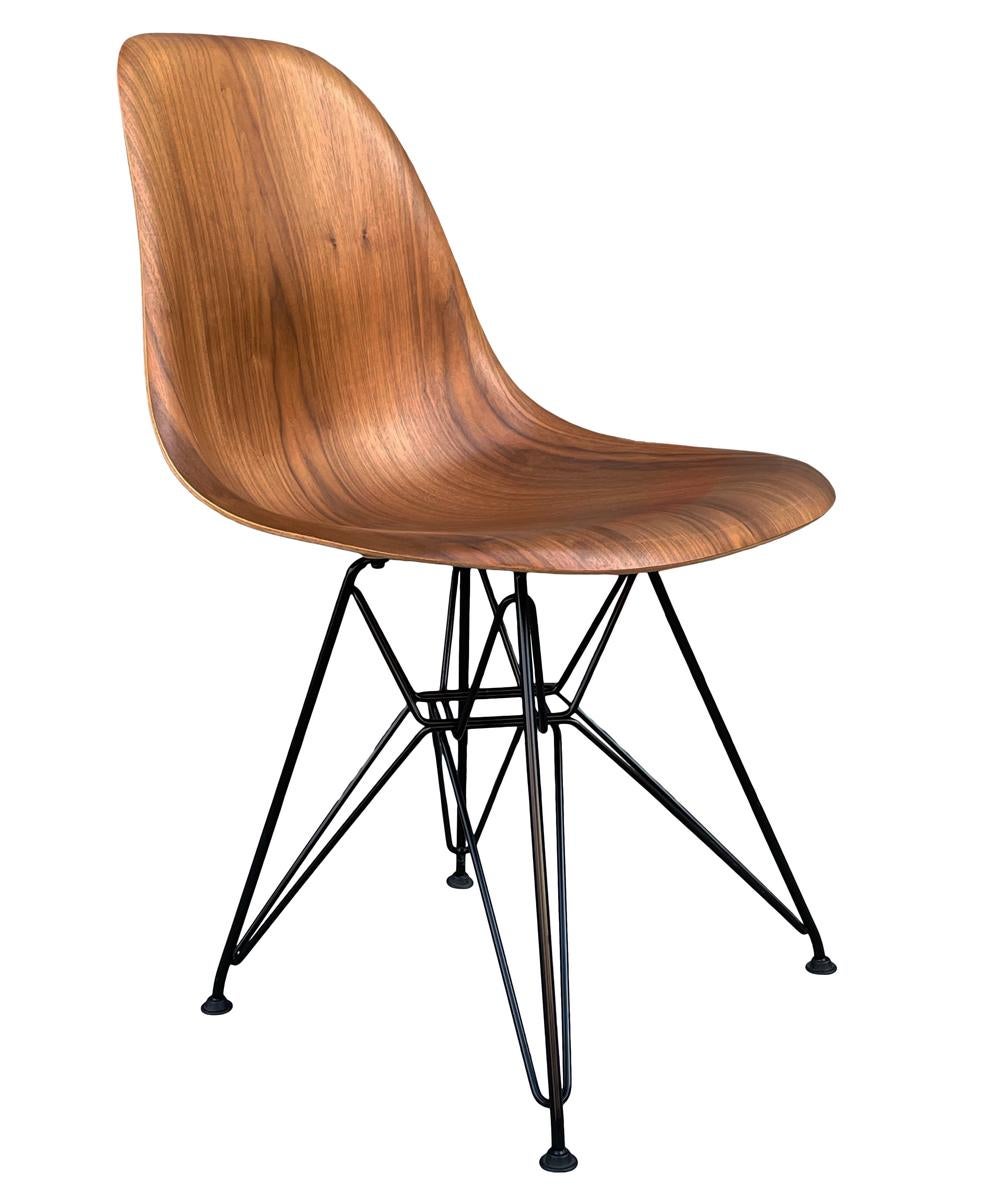 A complete set of molded plywood dining chairs designed by Charles Eames and produced by Herman Miller. These feature beautifully grained walnut shells with black Eiffel tower chair bases. Price includes 8 chairs as shown. Manufacture labels to each