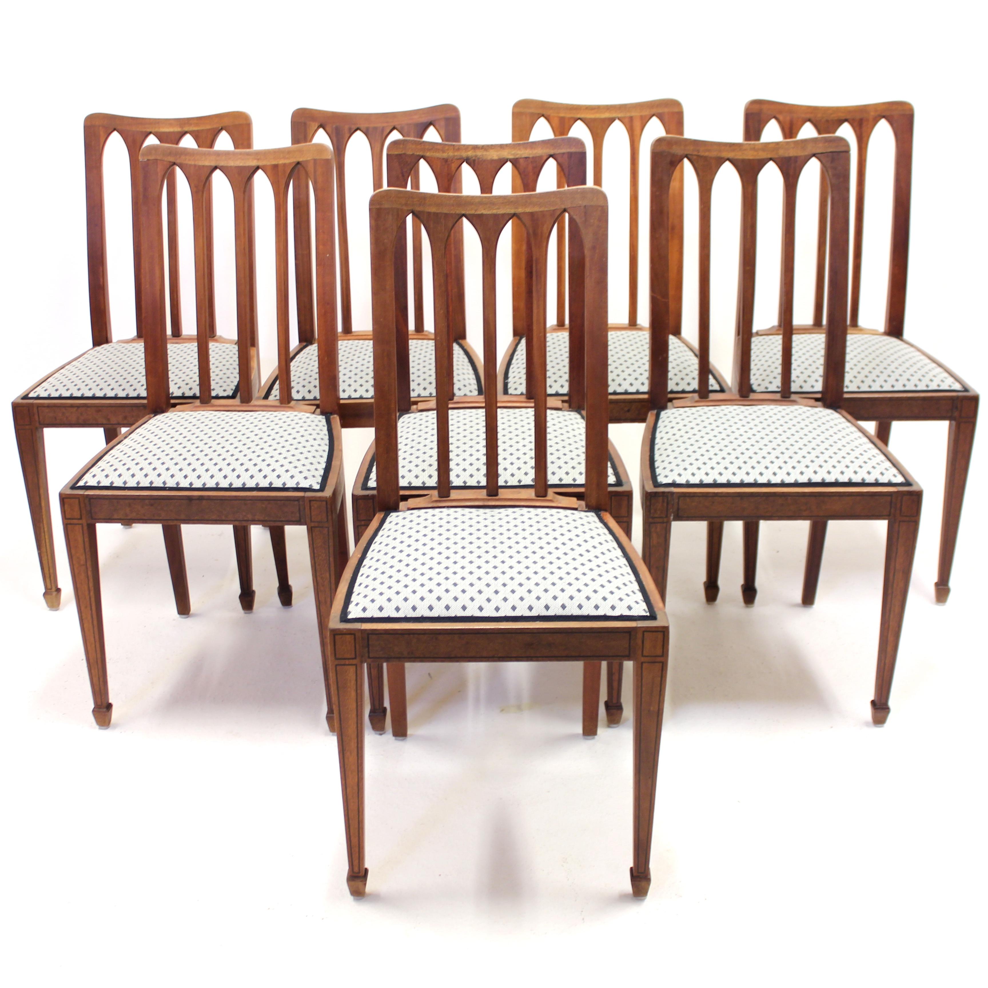 Set of 8 oak Arts & Crafts chairs with dark outlined inlays on the frames, made in the early 20th century. The back rests has four arches each, a very architectural element, in a very clean and minimalist design. Especially for being from the period