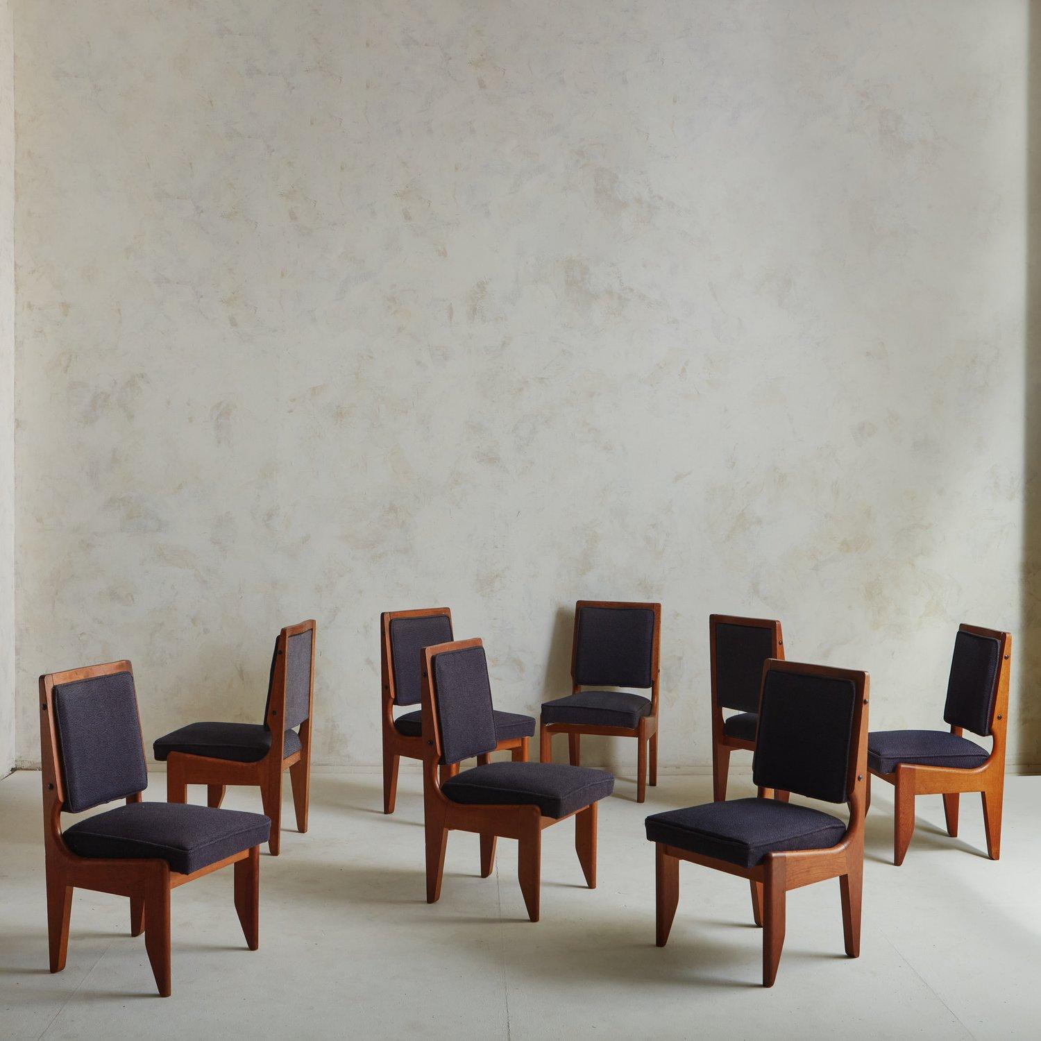 A set of 8 dining chairs by French design duo Guillerme et Chambron. These chairs have stained oak frames featuring beautiful craftsmanship and subtly tapered legs. They have upholstered seats and backs, which retain their original purple