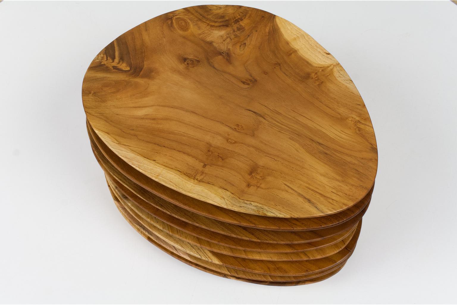 Set of 8 oval shaped and hand carved trays or serving platters in teak. The grain and coloring of the wood is beautiful. Each plate has a different coloring.